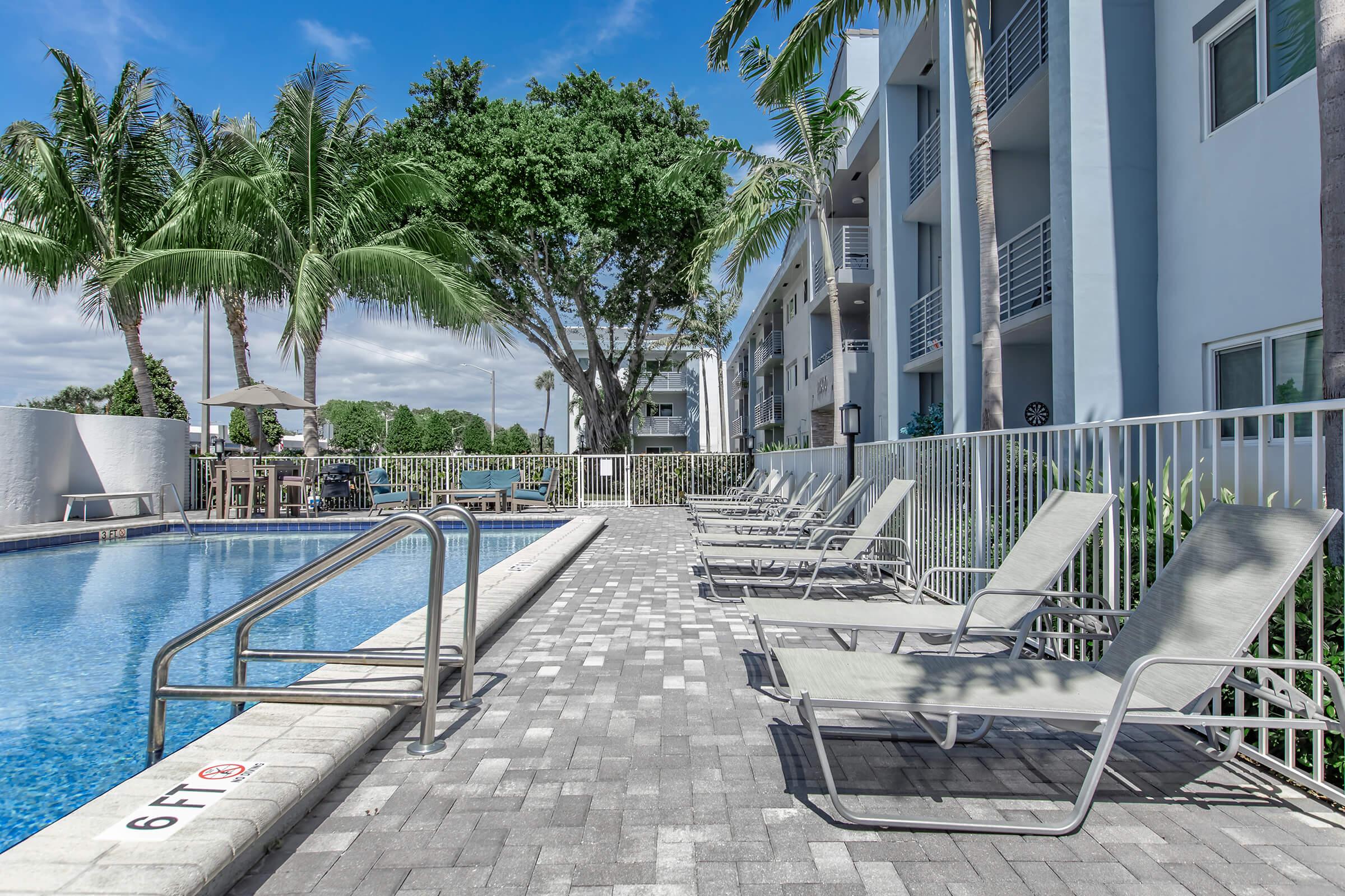 a bench on a sidewalk next to a pool of water