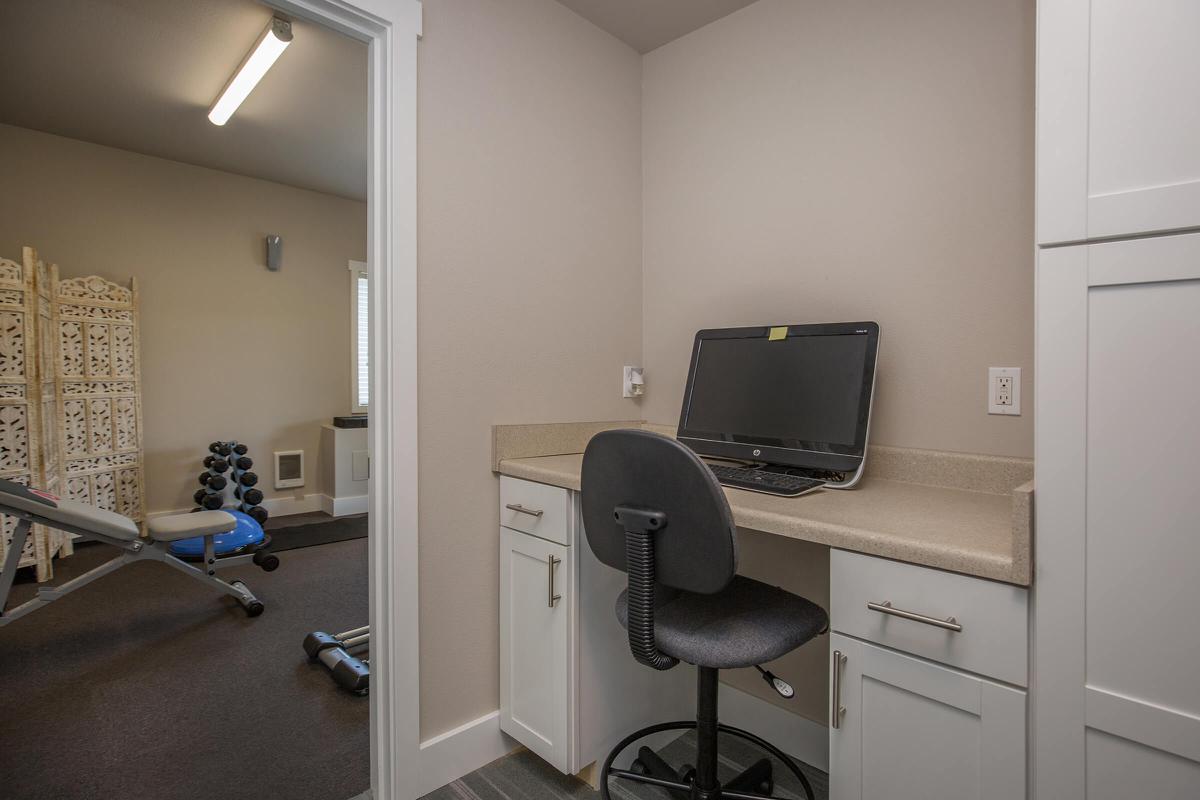 a desk with a computer and a chair in a room