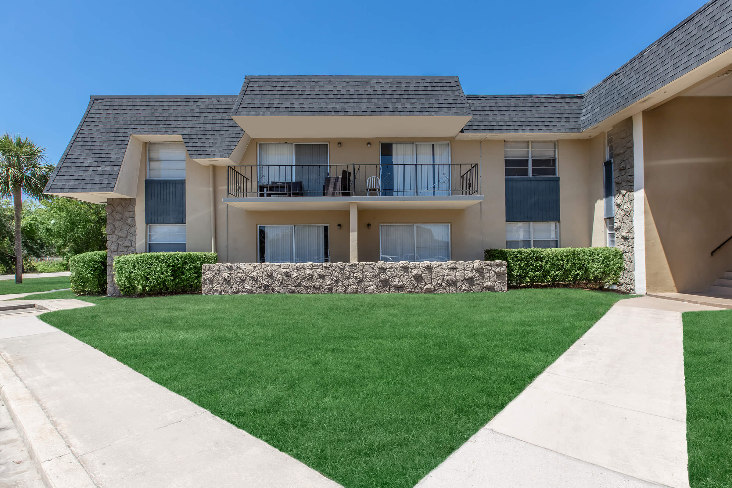 a large brick building with grass in front of a house