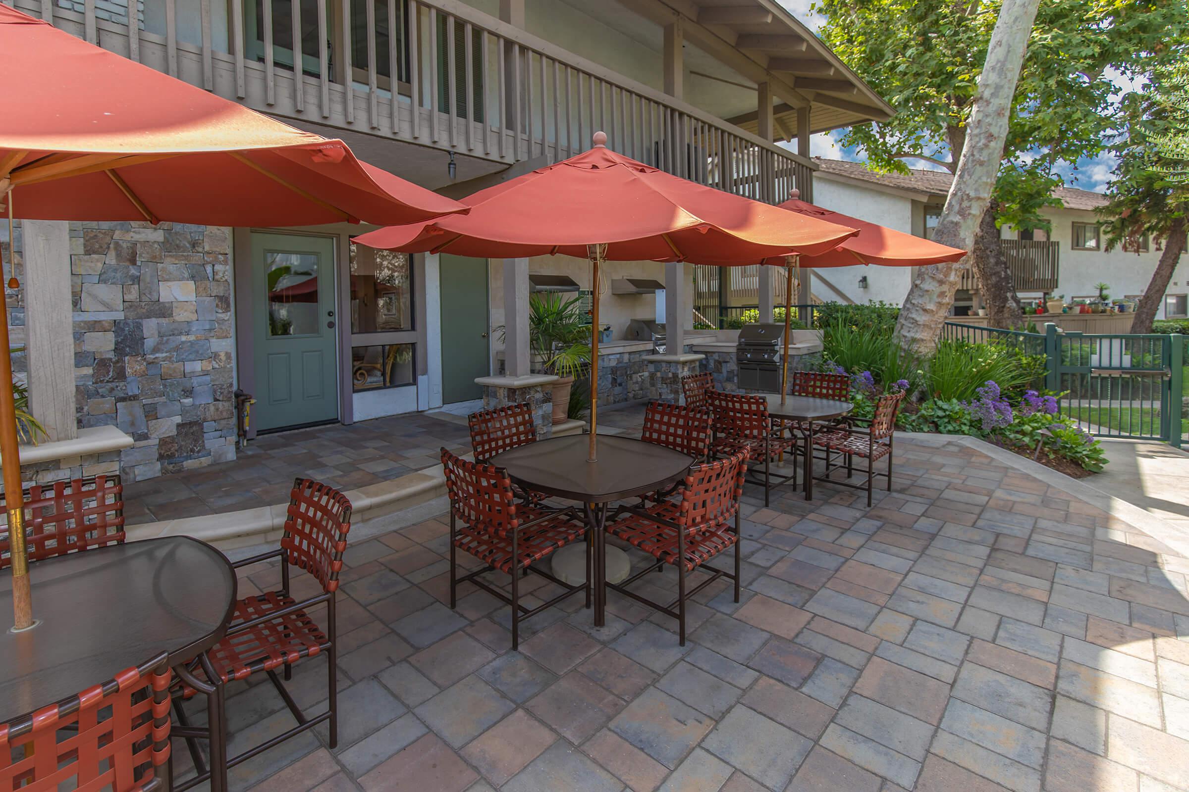 tables and chairs with red umbrellas