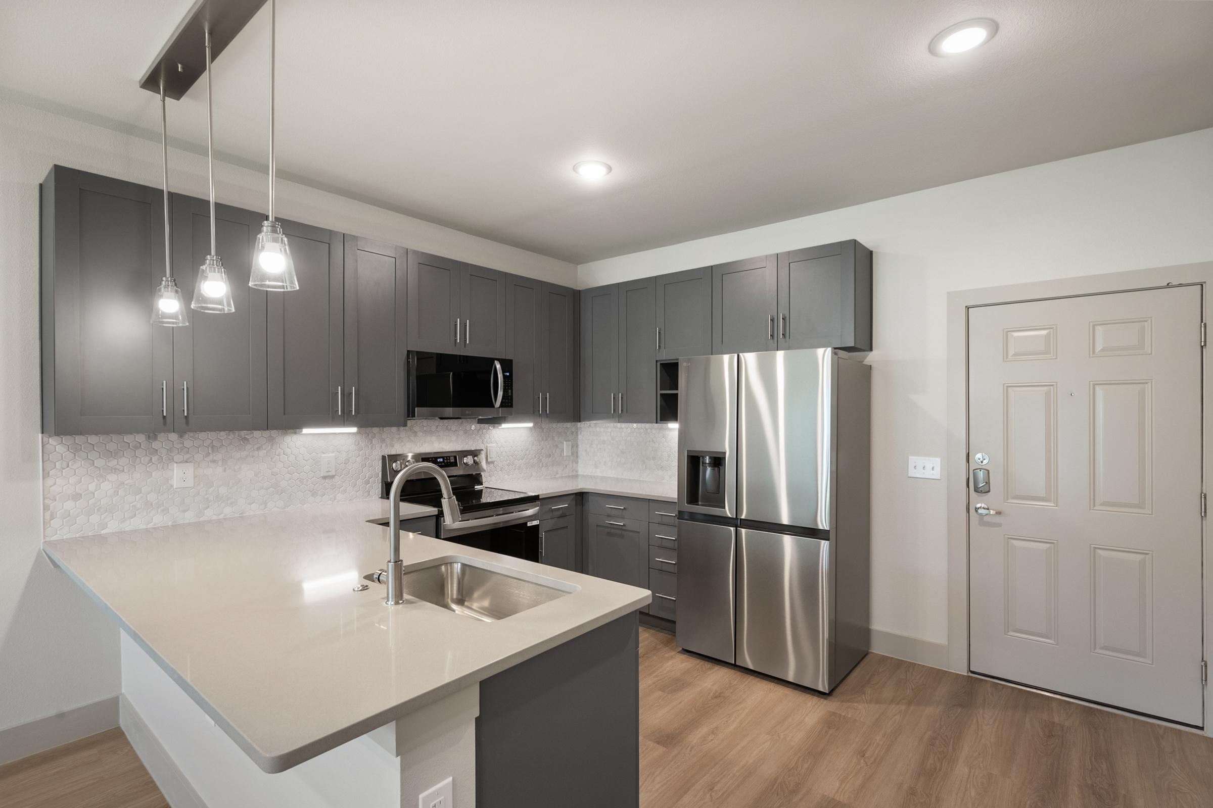 Modern kitchen in the A1 Floor Plan featuring stainless steel appliances, quartz countertops, and sleek cabinetry.