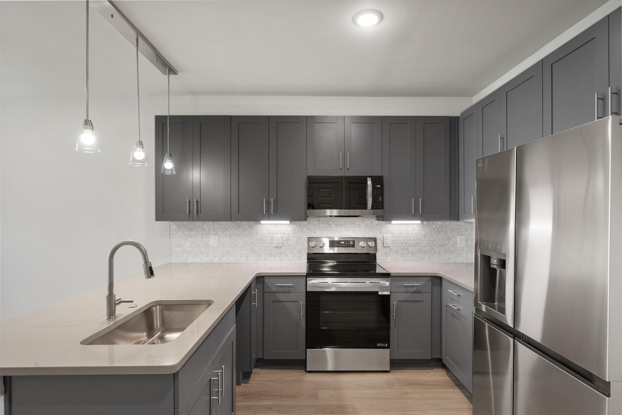 Modern kitchen in the A1 Floor Plan featuring stainless steel appliances, quartz countertops, and sleek cabinetry.