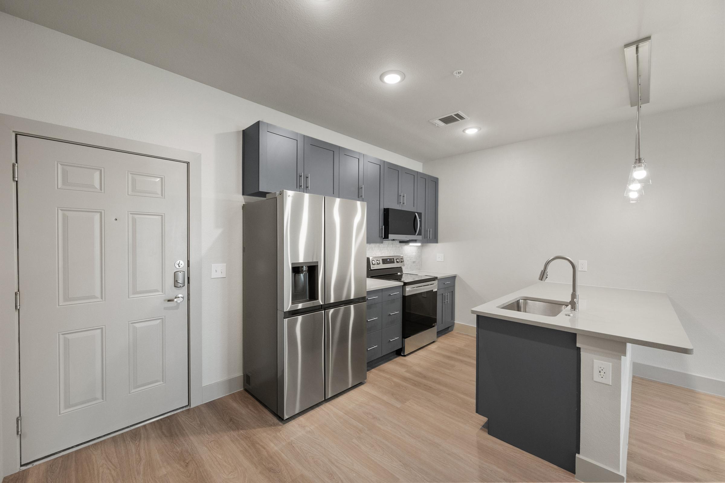 Contemporary kitchen in the A2 Floor Plan with quartz countertops, stainless steel appliances, pendant lighting, and stylish cabinetry.