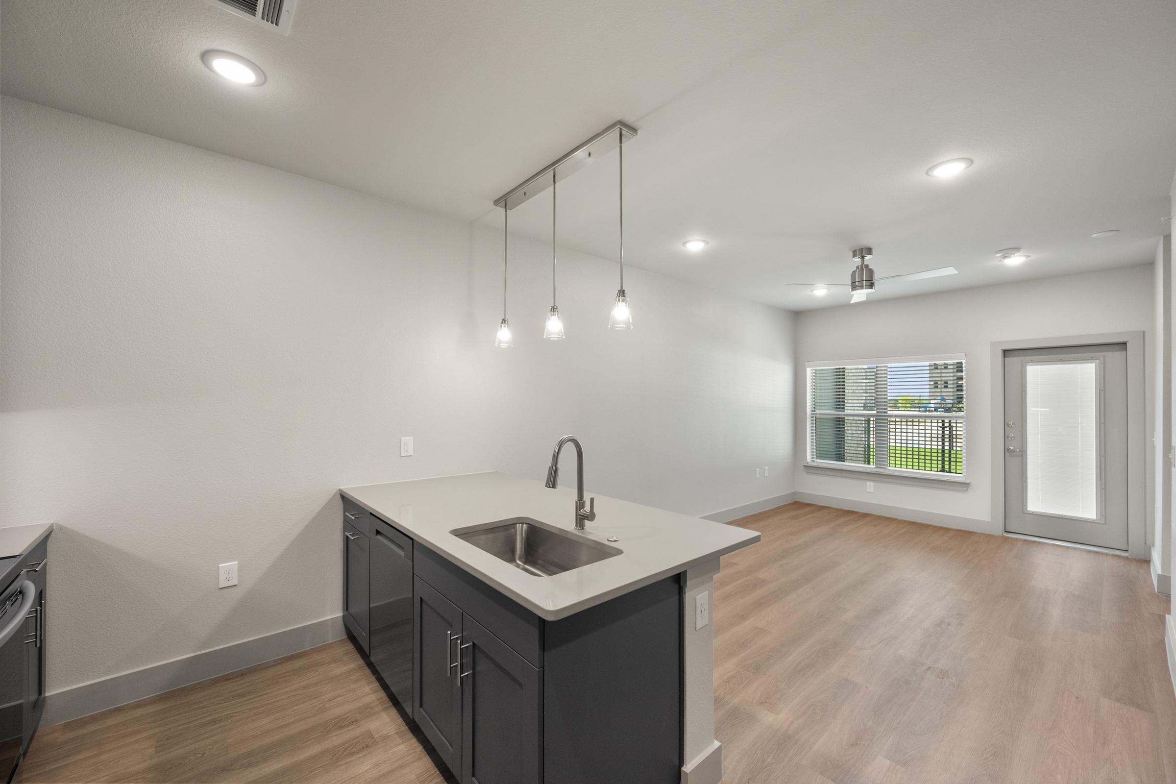 Contemporary kitchen in the A2 Floor Plan with quartz countertops, stainless steel appliances, pendant lighting, and stylish cabinetry.