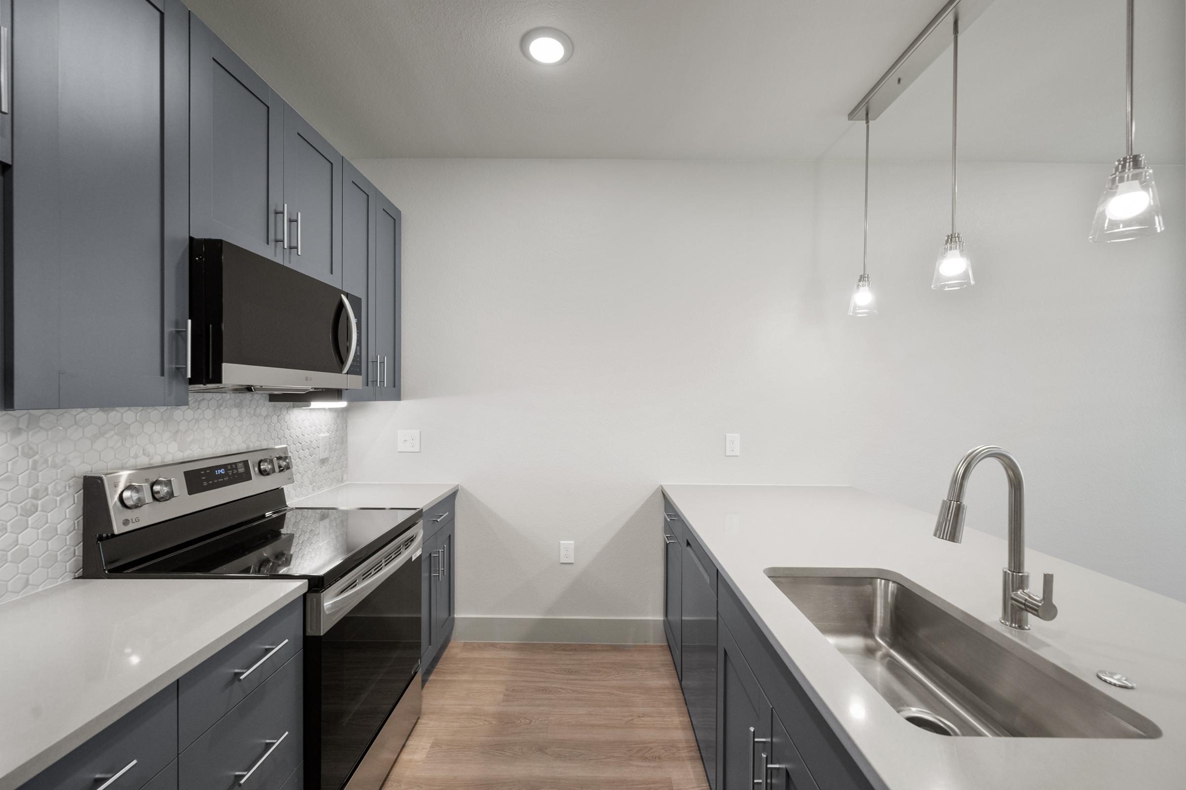 Contemporary kitchen in the A2 Floor Plan with quartz countertops, stainless steel appliances, pendant lighting, and stylish cabinetry.
