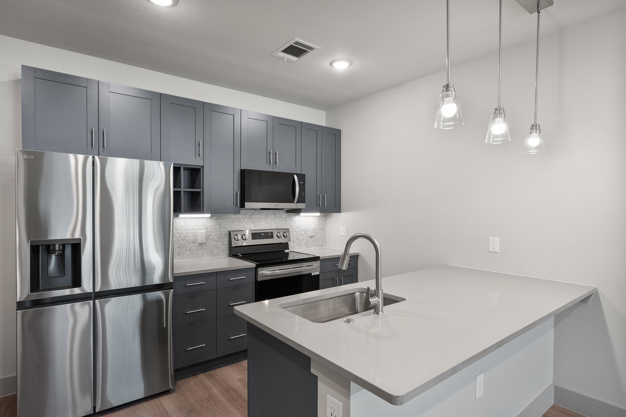Contemporary kitchen in the A2 Floor Plan with quartz countertops, stainless steel appliances, pendant lighting, and stylish cabinetry.