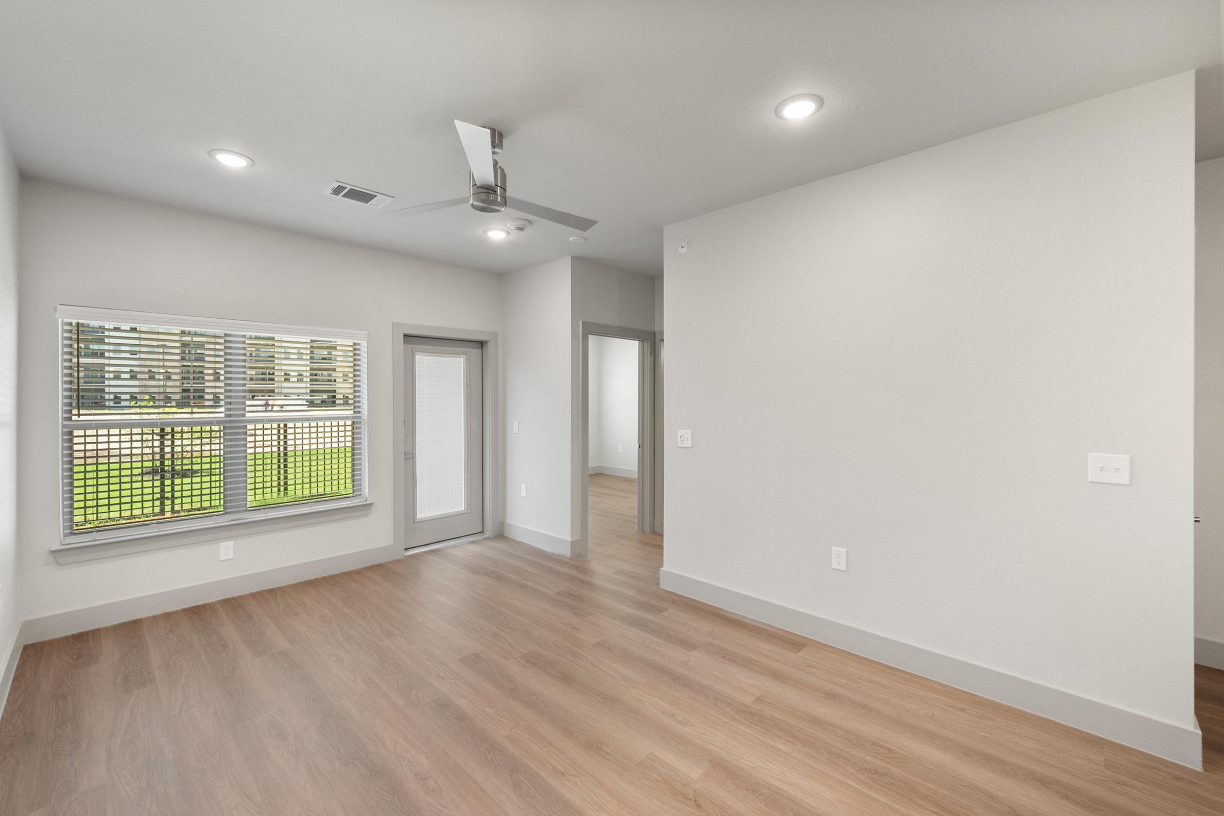 Open-concept living area in the A2 one-bedroom unit with high ceilings, large windows, and seamless flow to the kitchen and dining space.