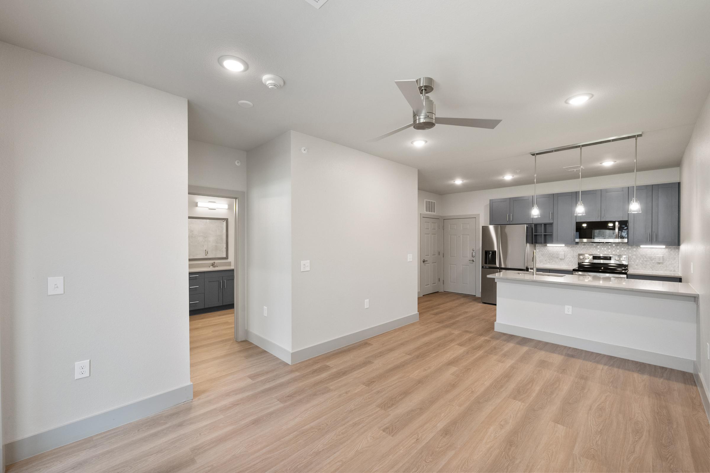Open-concept living area in the A2 one-bedroom unit with high ceilings, large windows, and seamless flow to the kitchen and dining space.