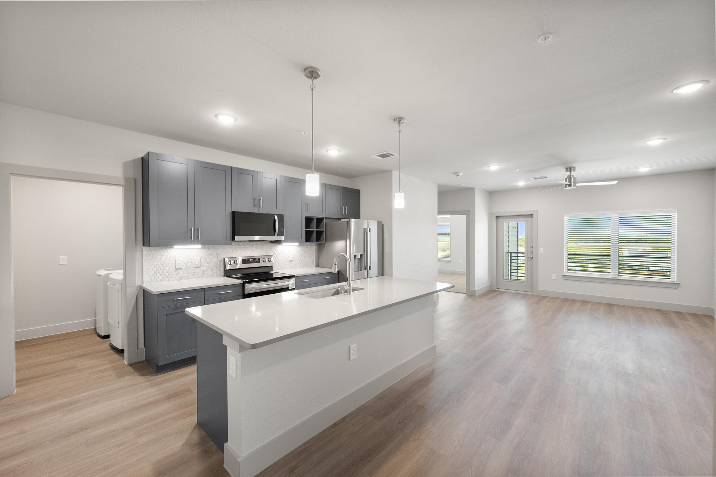Modern kitchen featuring pendant lighting, quartz countertops, and stainless steel appliances in the A3 one-bedroom unit.