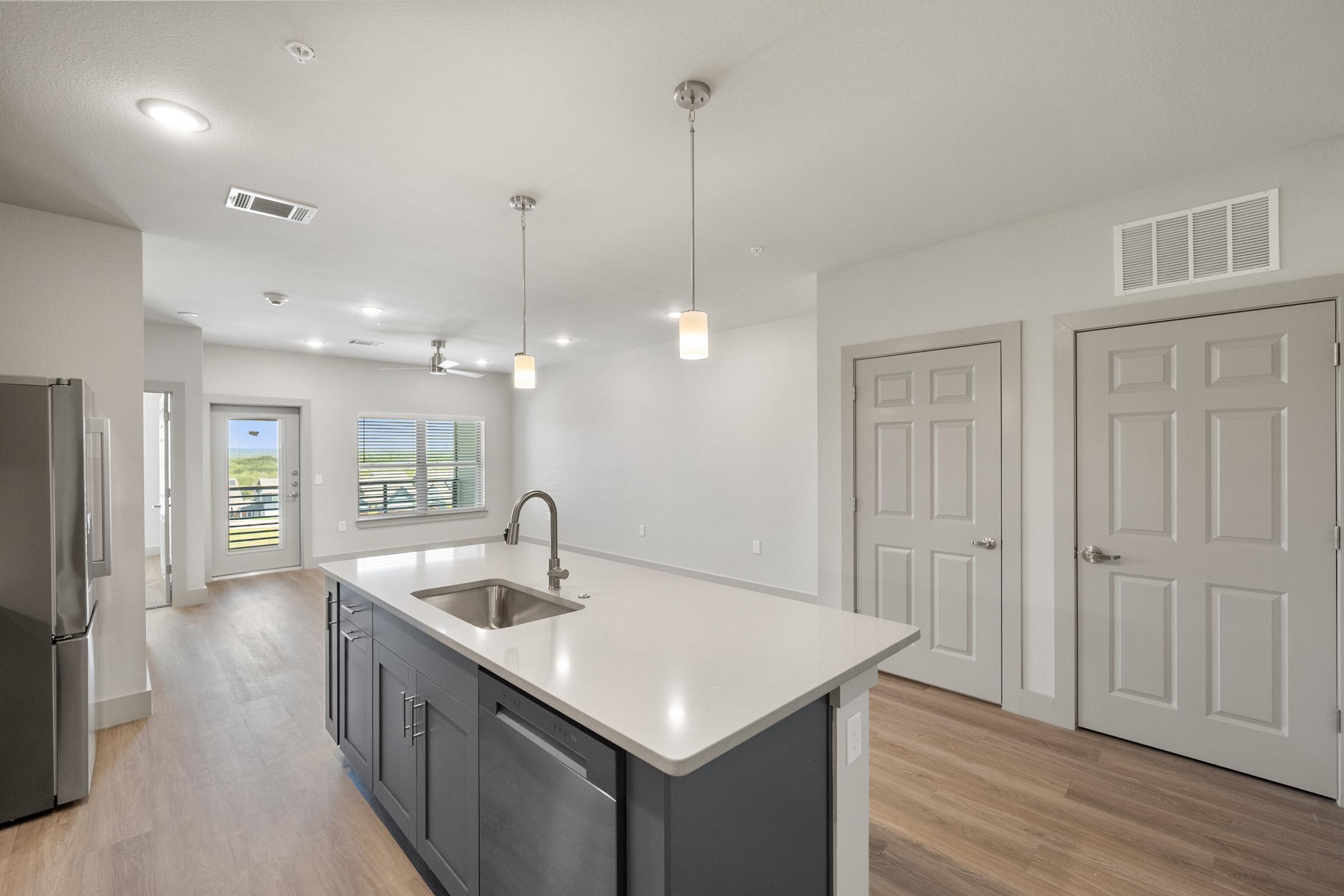 Modern kitchen featuring pendant lighting, quartz countertops, and stainless steel appliances in the A3 one-bedroom unit.