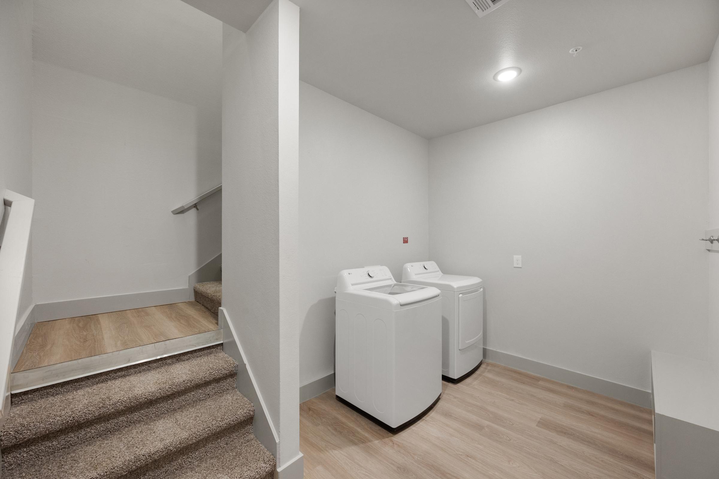 Laundry room located on the garage level in the A4 unit, featuring full-size washer and dryer with built-in shelving.