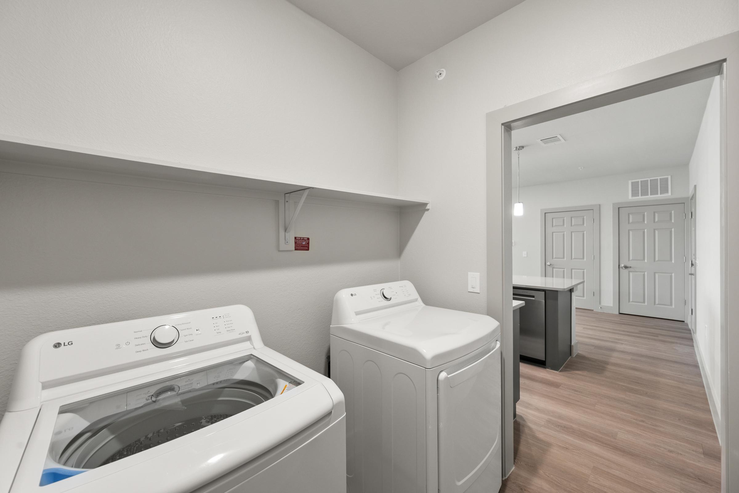 Dedicated laundry room in the B1 Floor Plan featuring full-size washer and dryer and built-in shelving for storage.