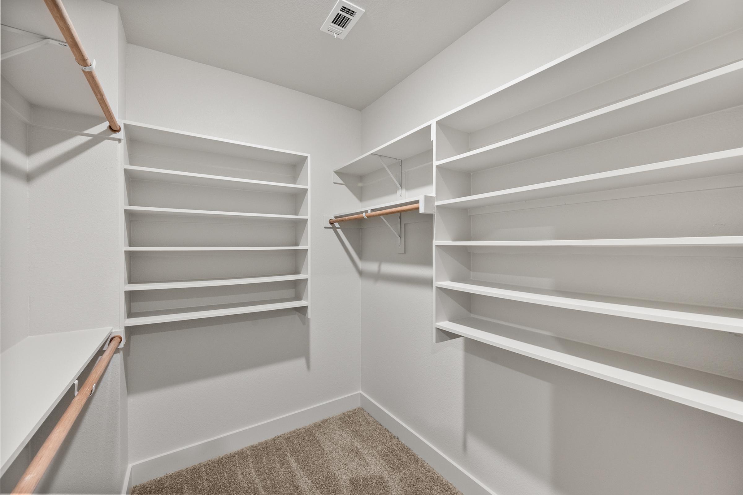 Secondary bedroom closet in the B1 Floor Plan at The Emma Apartments offering ample hanging space and shelving for organized storage.