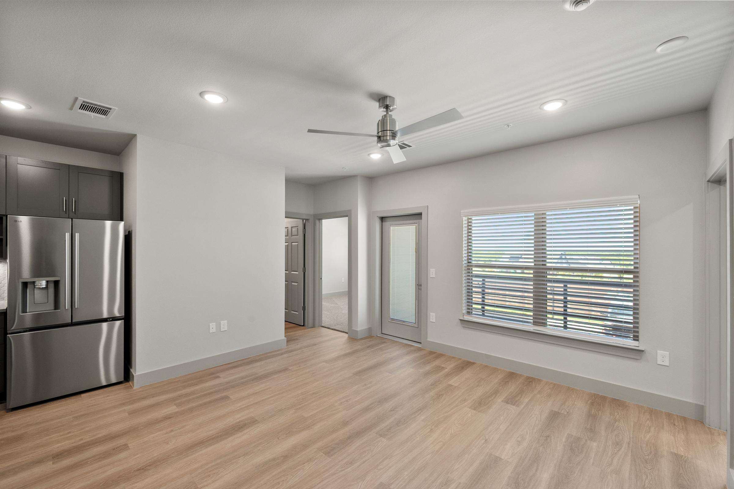 Spacious living room in the B2 unit with open-concept design, high ceilings, ceiling fan, and large windows for natural light.