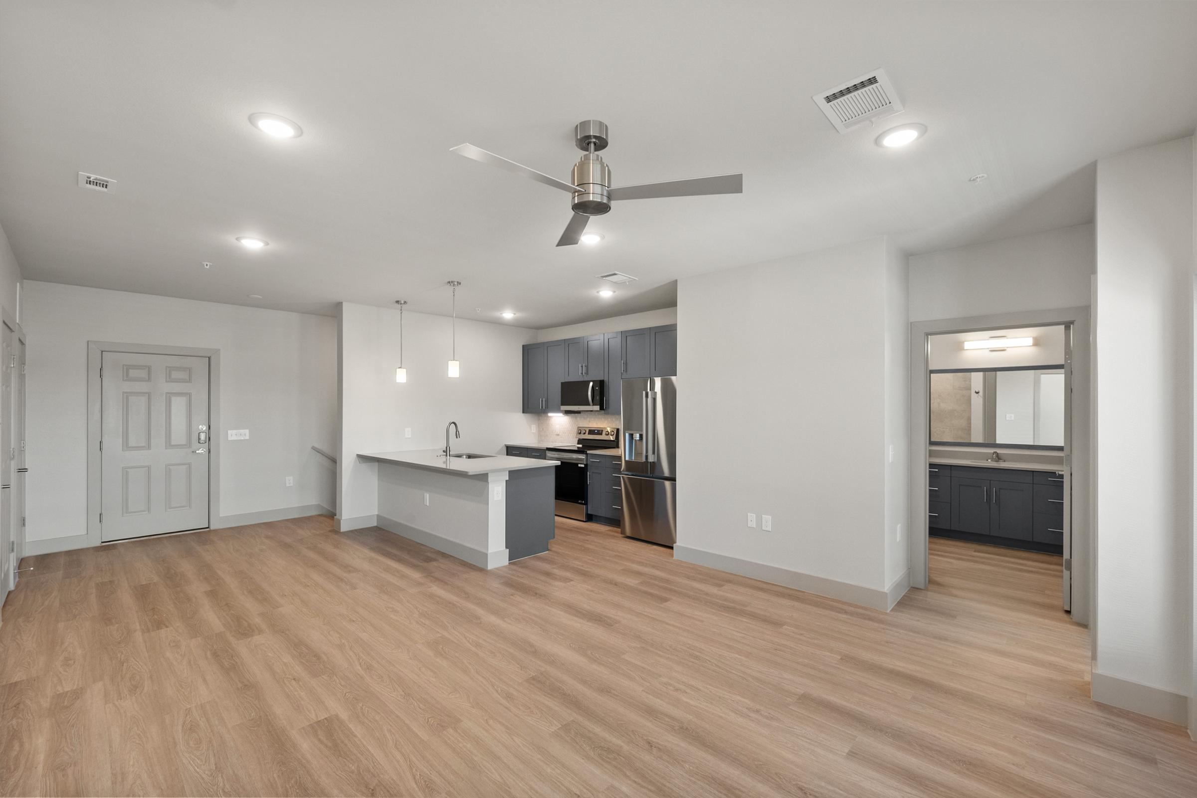 Spacious living room in the B2 unit with open-concept design, high ceilings, ceiling fan, and large windows for natural light.