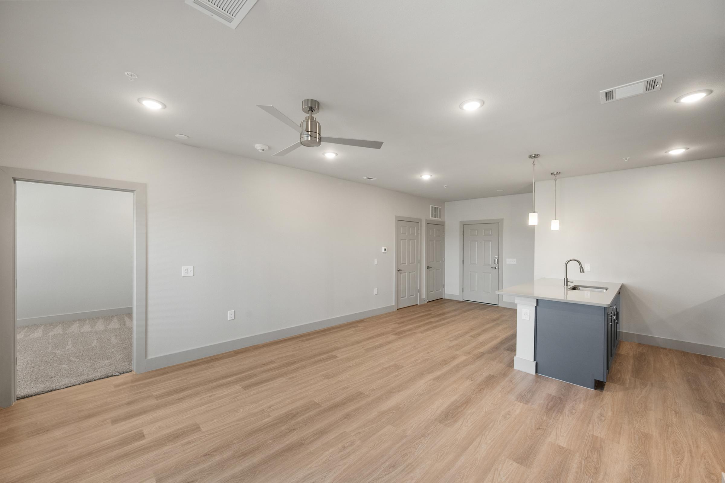 Spacious living room in the B2 unit with open-concept design, high ceilings, ceiling fan, and large windows for natural light.