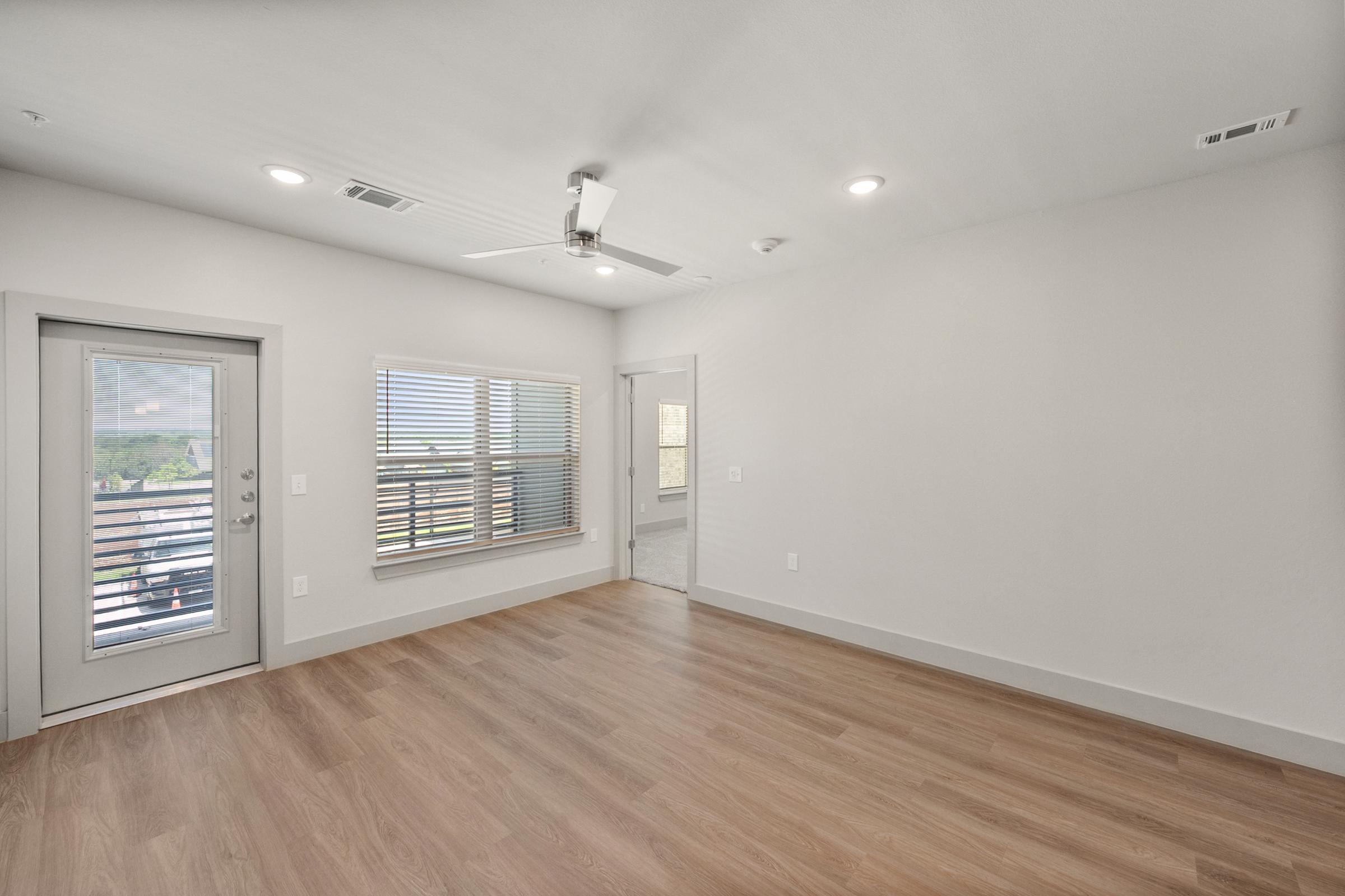 Spacious living room in the B2 unit with open-concept design, high ceilings, ceiling fan, and large windows for natural light.