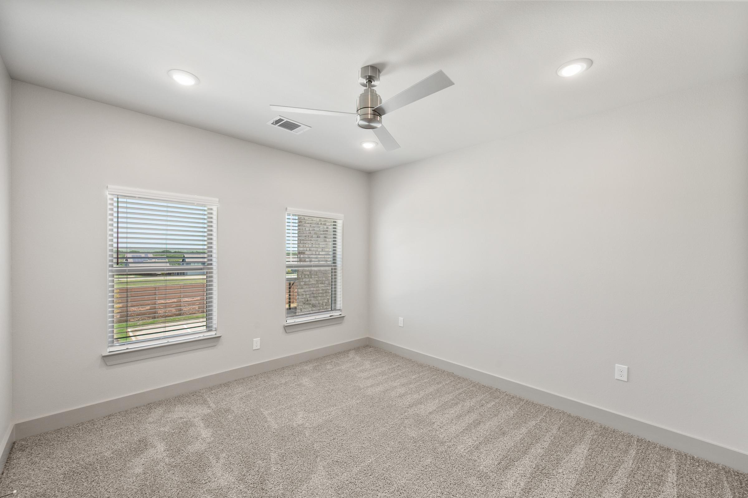 Primary bedroom in the B2 unit featuring plush carpet, natural light, and direct access to a large walk-in closet and ensuite bathroom.