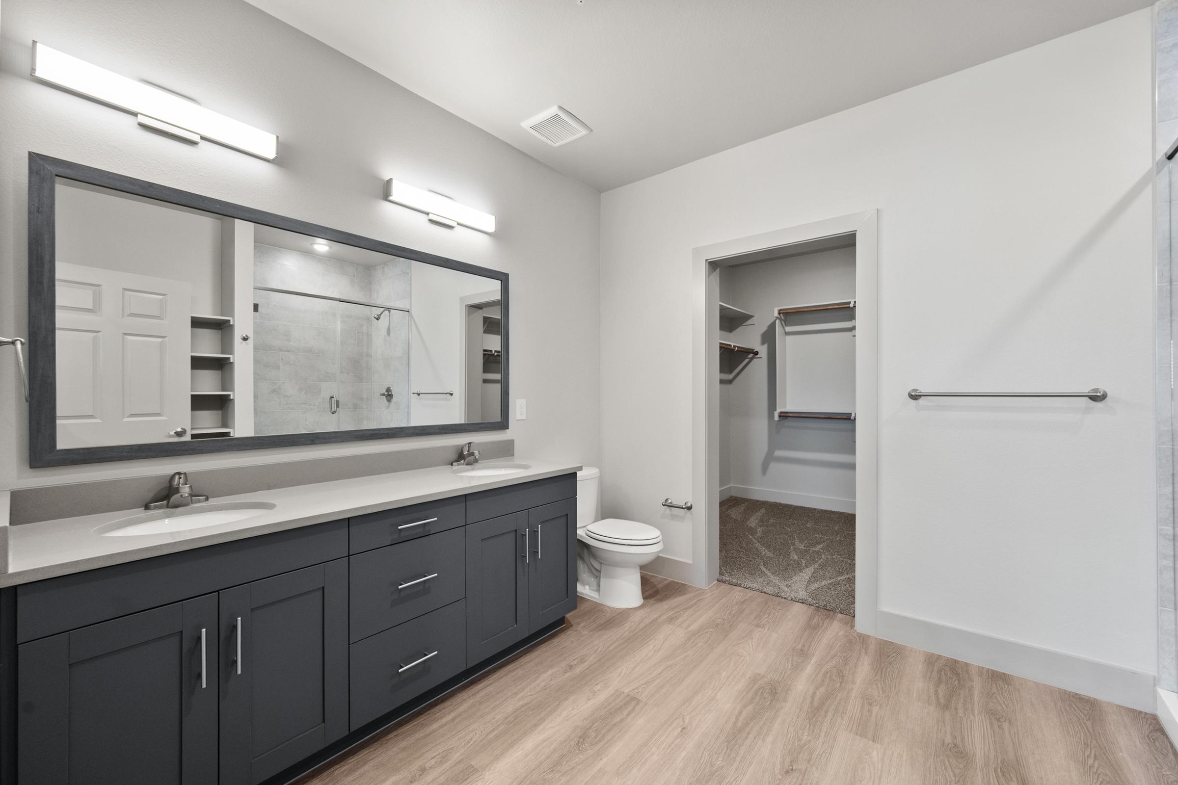 Ensuite primary bathroom with dual vanities, sleek fixtures, and a spacious walk-in shower for a spa-like experience.