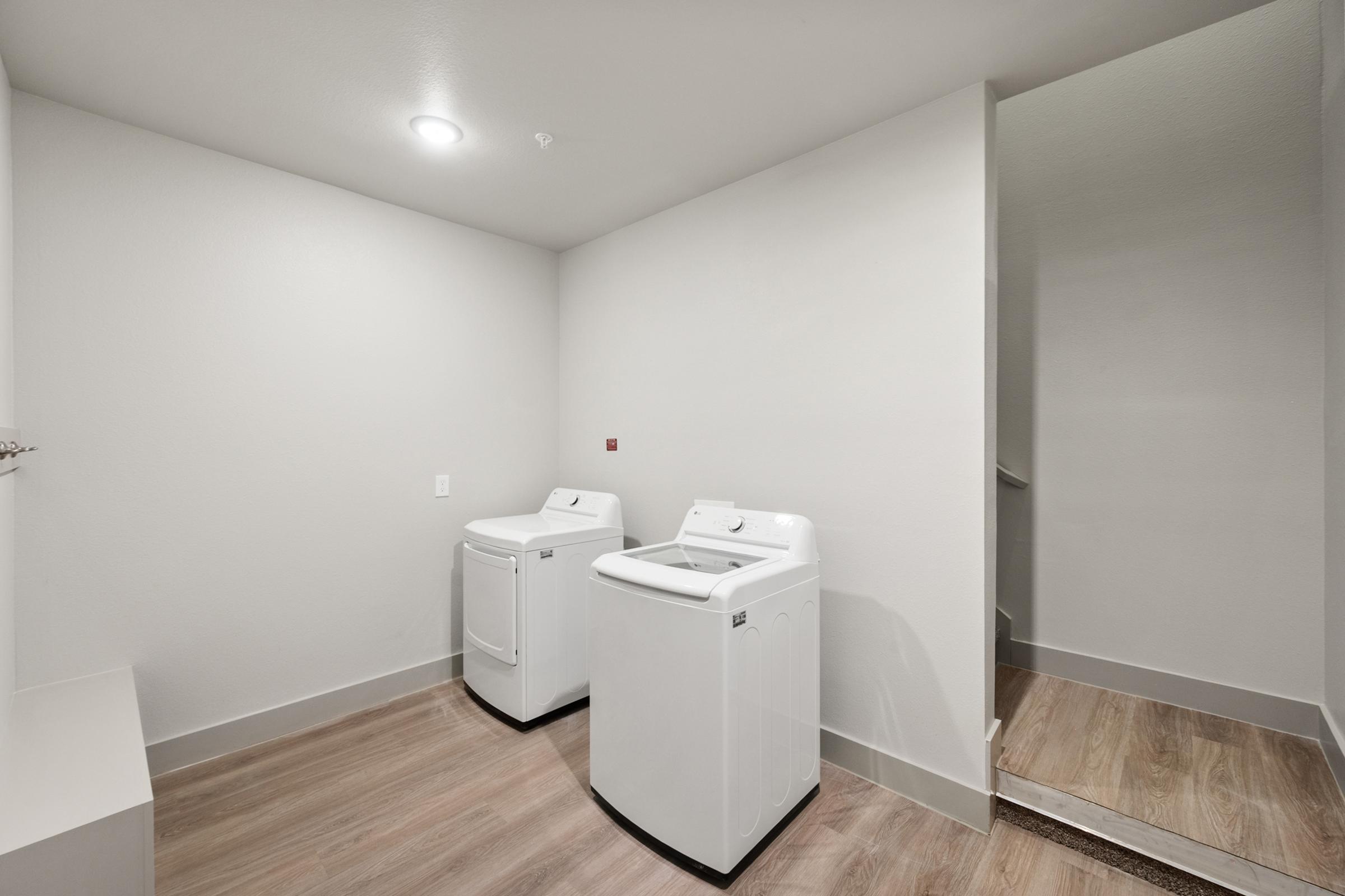 In-unit laundry room in the B2 Floor Plan located on the garage level, featuring full-size washer and dryer and built-in shelving.
