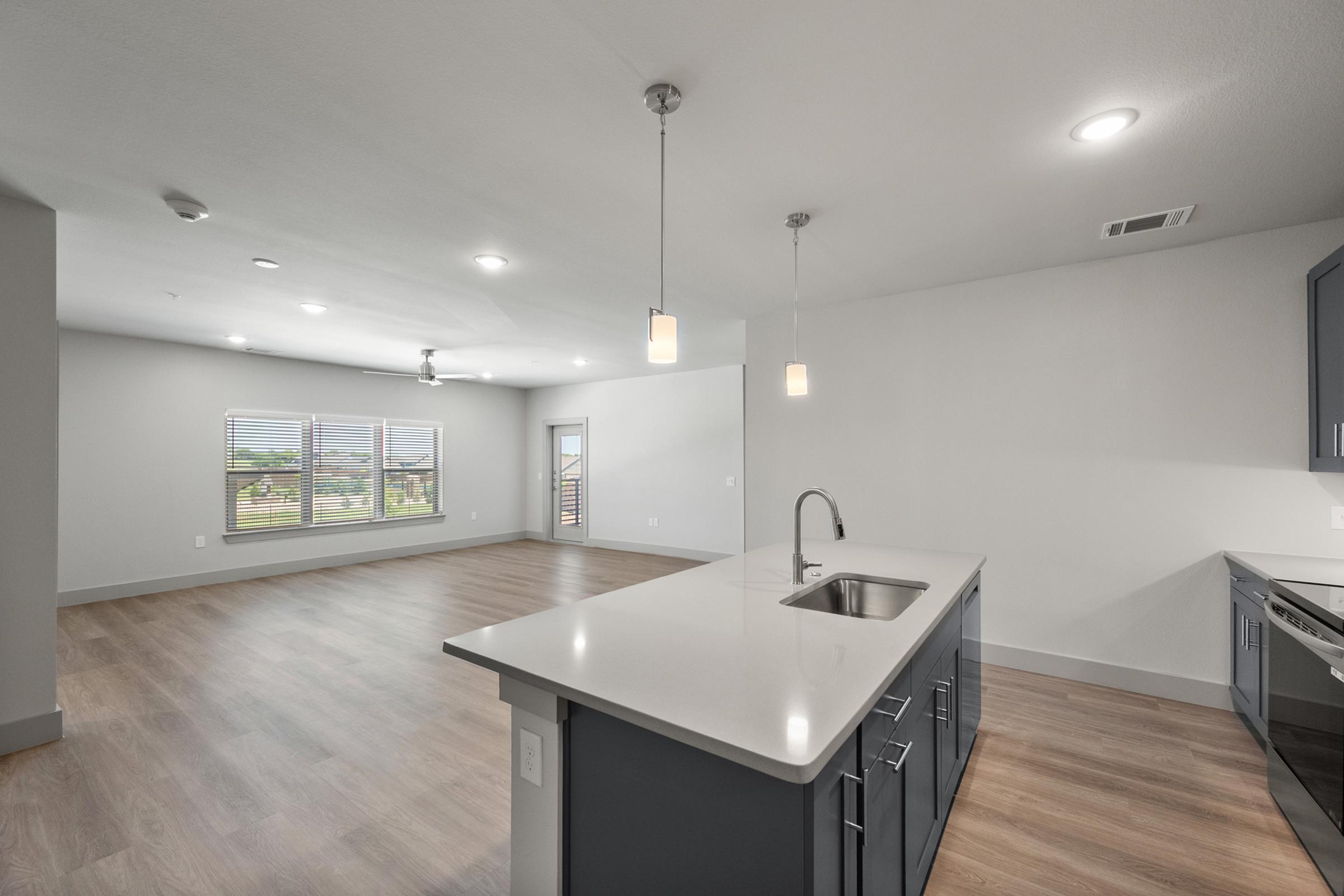 Spacious kitchen in the C1 Floor Plan featuring quartz countertops, stainless steel appliances, pendant lighting, soft-close cabinets, a built-in wine rack, and a large center island.