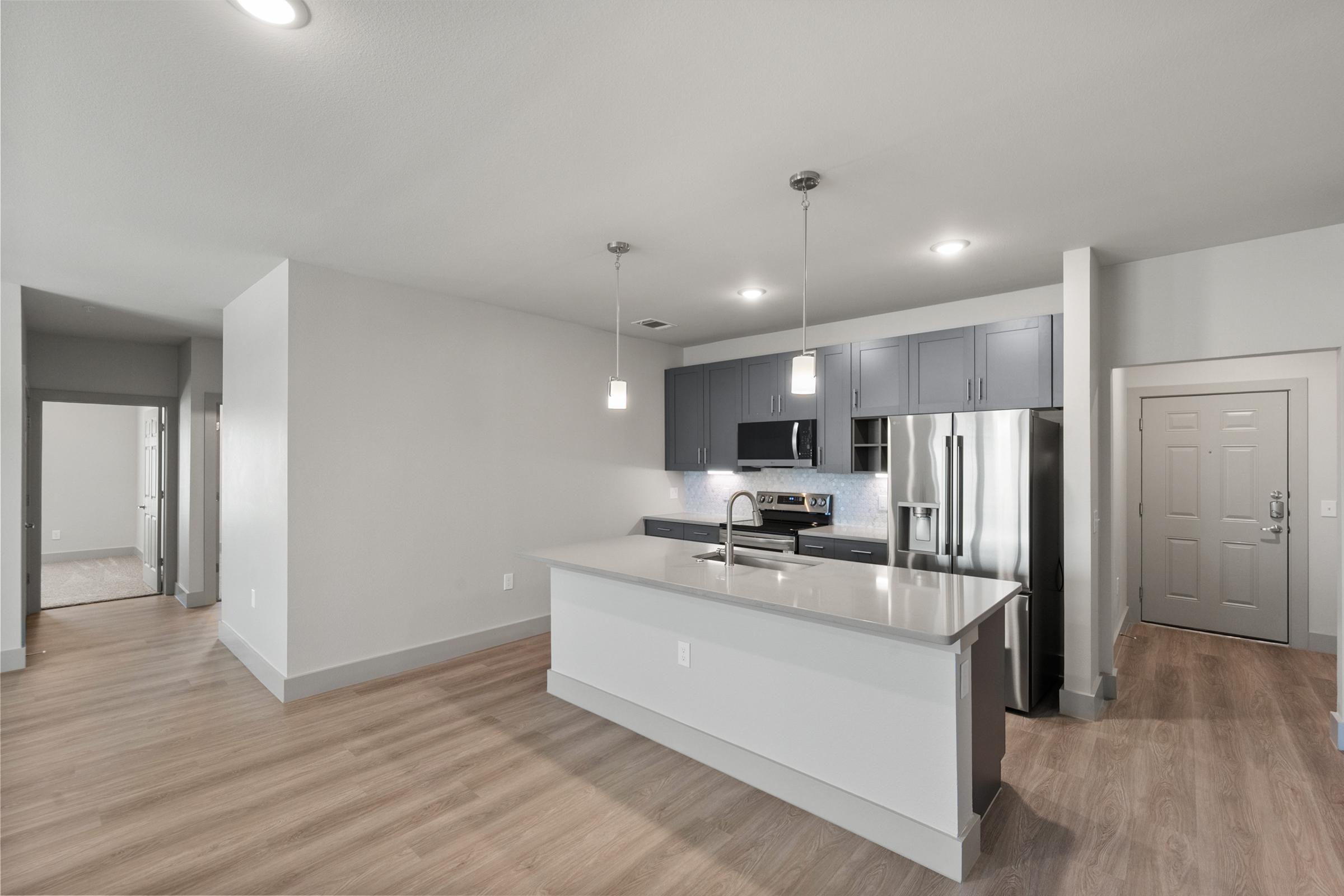 Spacious kitchen in the C1 Floor Plan featuring quartz countertops, stainless steel appliances, pendant lighting, soft-close cabinets, a built-in wine rack, and a large center island.