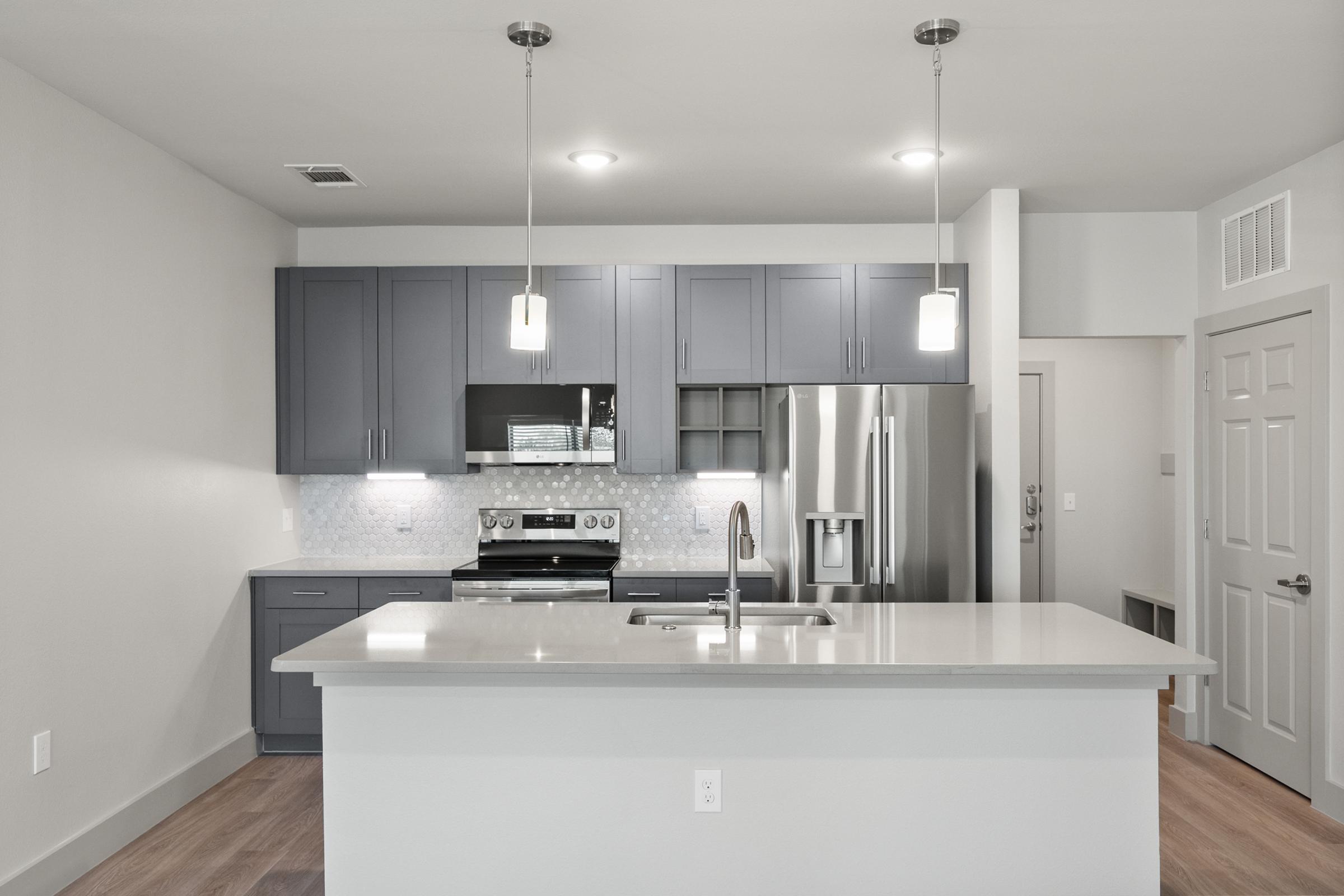 Spacious kitchen in the C1 Floor Plan featuring quartz countertops, stainless steel appliances, pendant lighting, soft-close cabinets, a built-in wine rack, and a large center island.