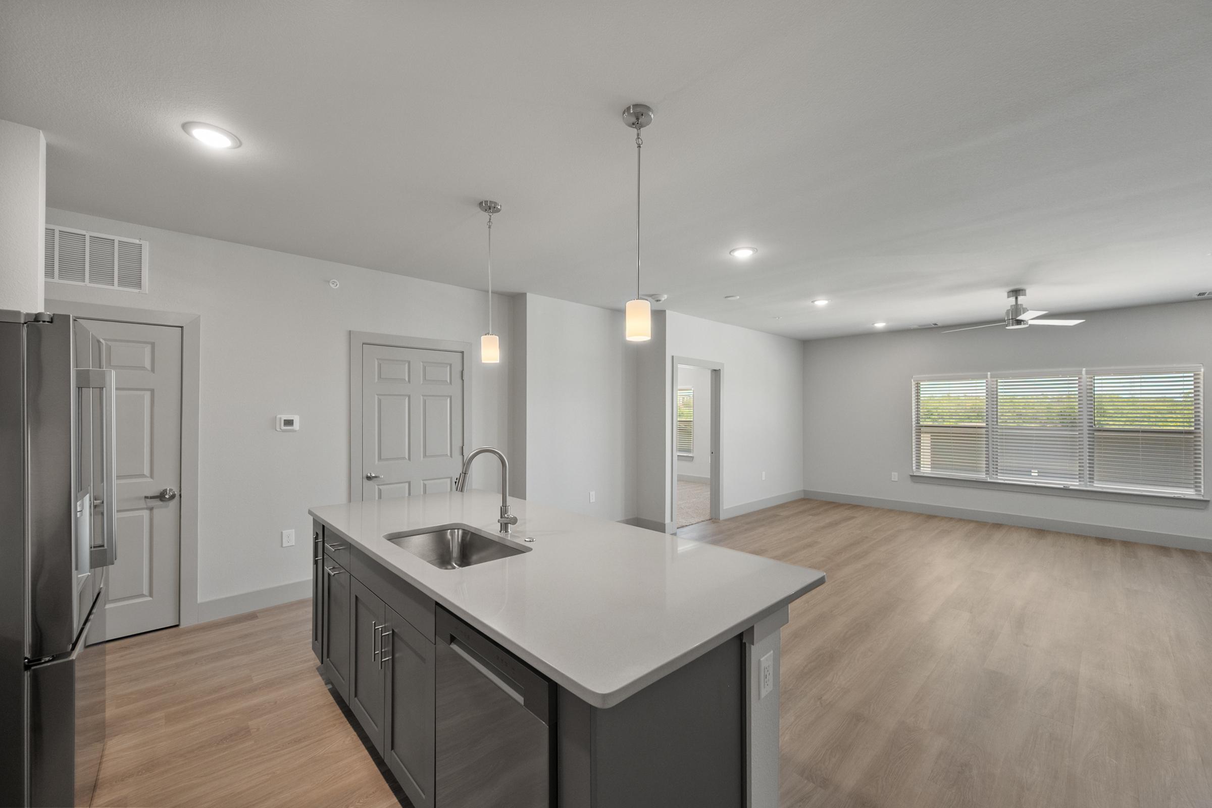 Spacious kitchen in the C1 Floor Plan featuring quartz countertops, stainless steel appliances, pendant lighting, soft-close cabinets, a built-in wine rack, and a large center island.