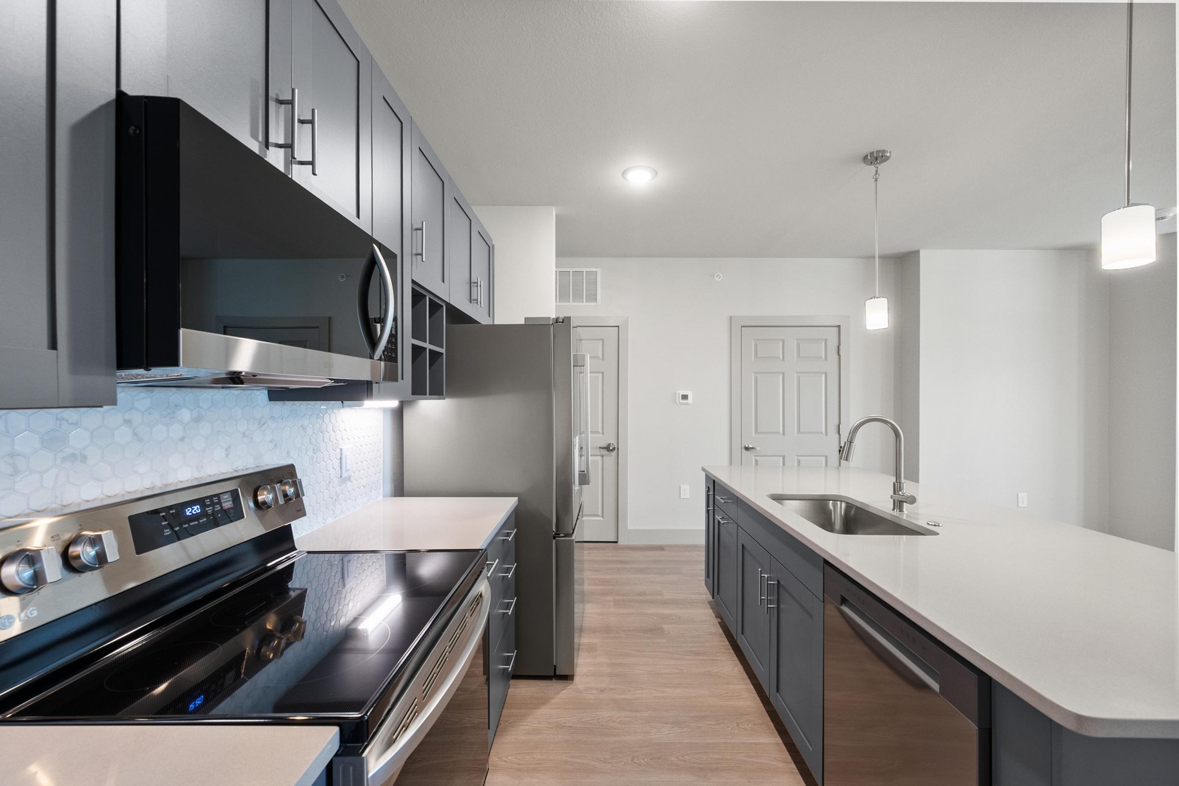 Spacious kitchen in the C1 Floor Plan featuring quartz countertops, stainless steel appliances, pendant lighting, soft-close cabinets, a built-in wine rack, and a large center island.
