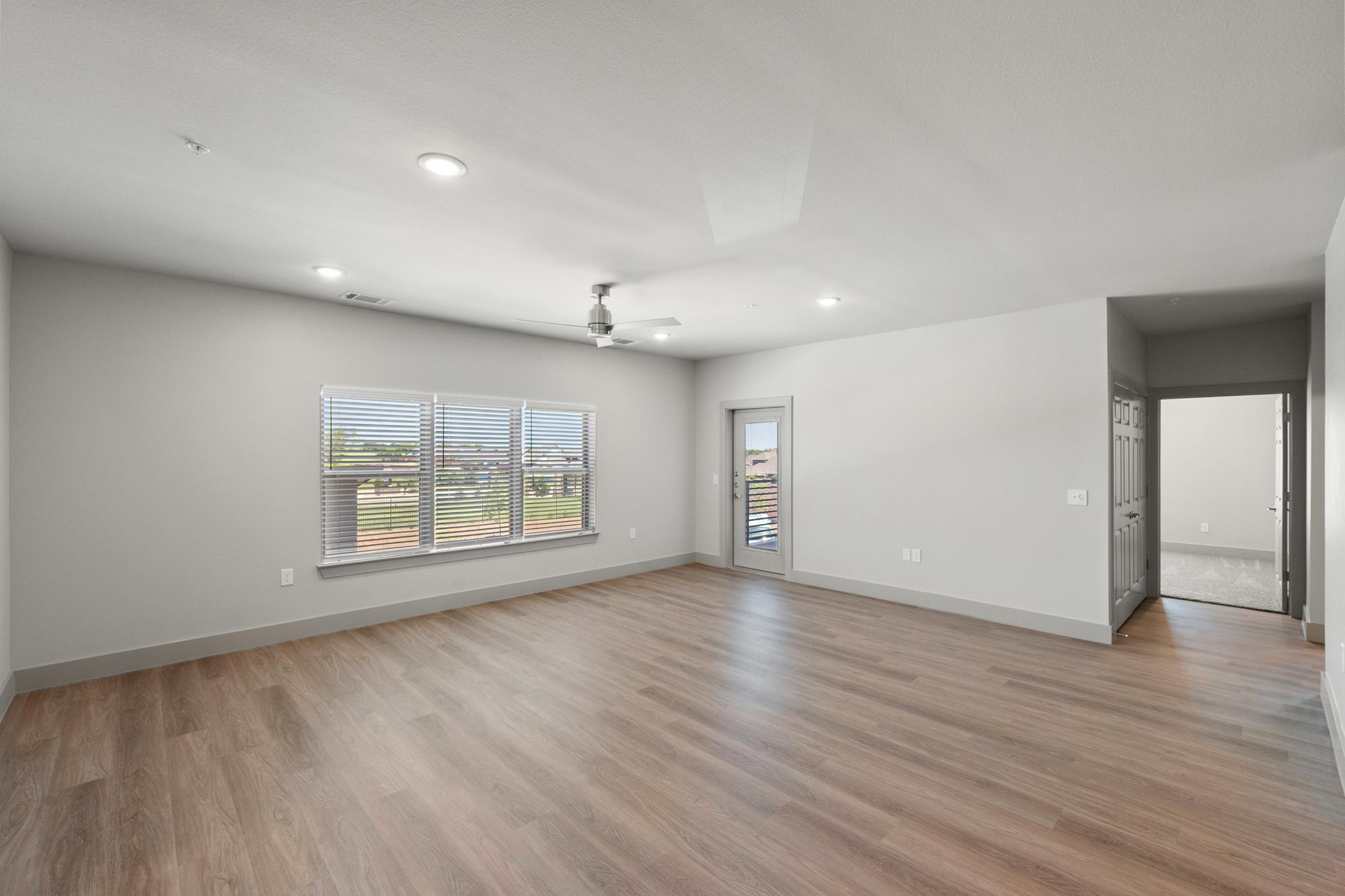 Large open-concept living room in the C1 unit with high ceilings, ceiling fan, and natural light flowing through large windows.