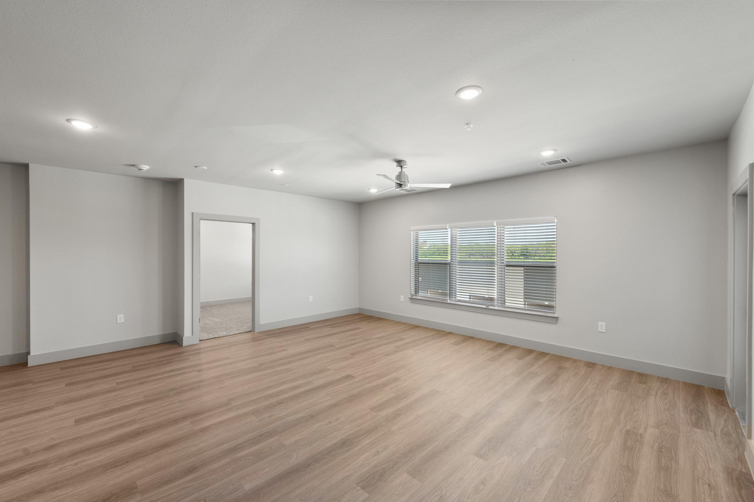 Large open-concept living room in the C1 unit with high ceilings, ceiling fan, and natural light flowing through large windows.