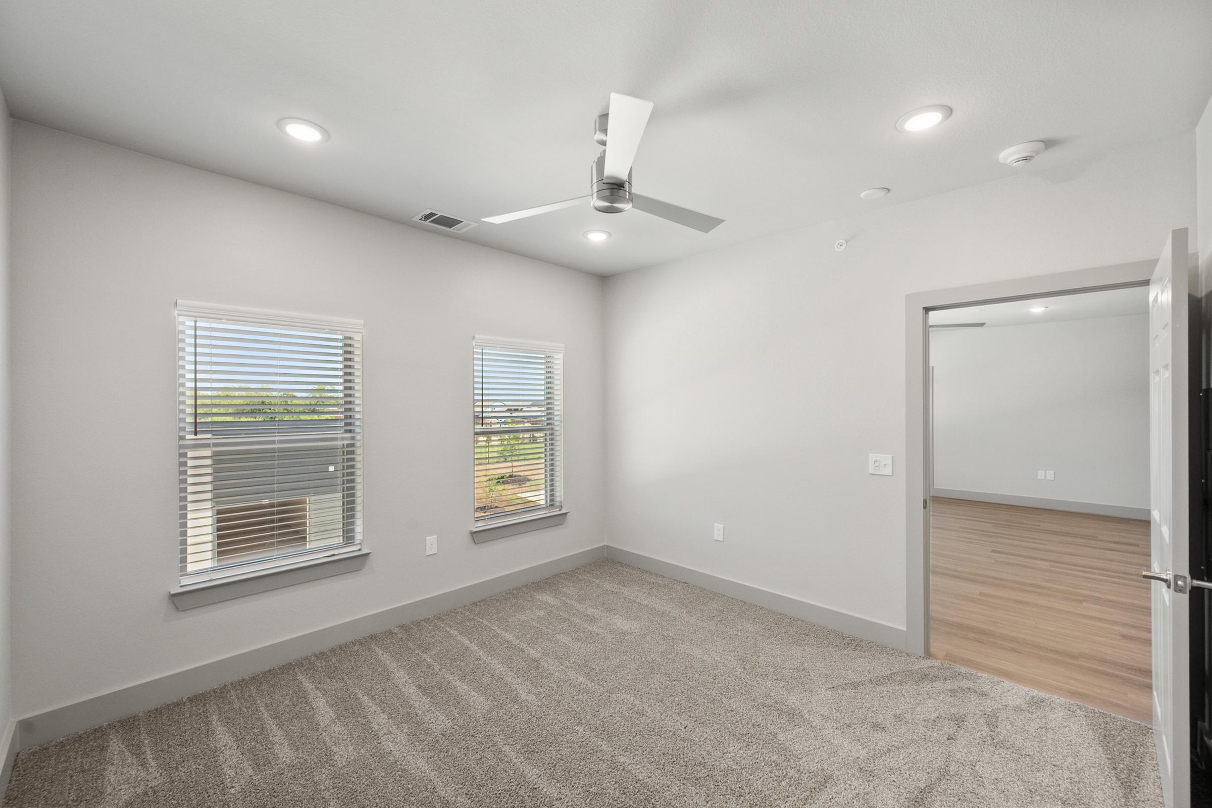 Primary bedroom in the C1 unit with plush carpet, oversized windows, and direct access to an ensuite bathroom and walk-in closet.