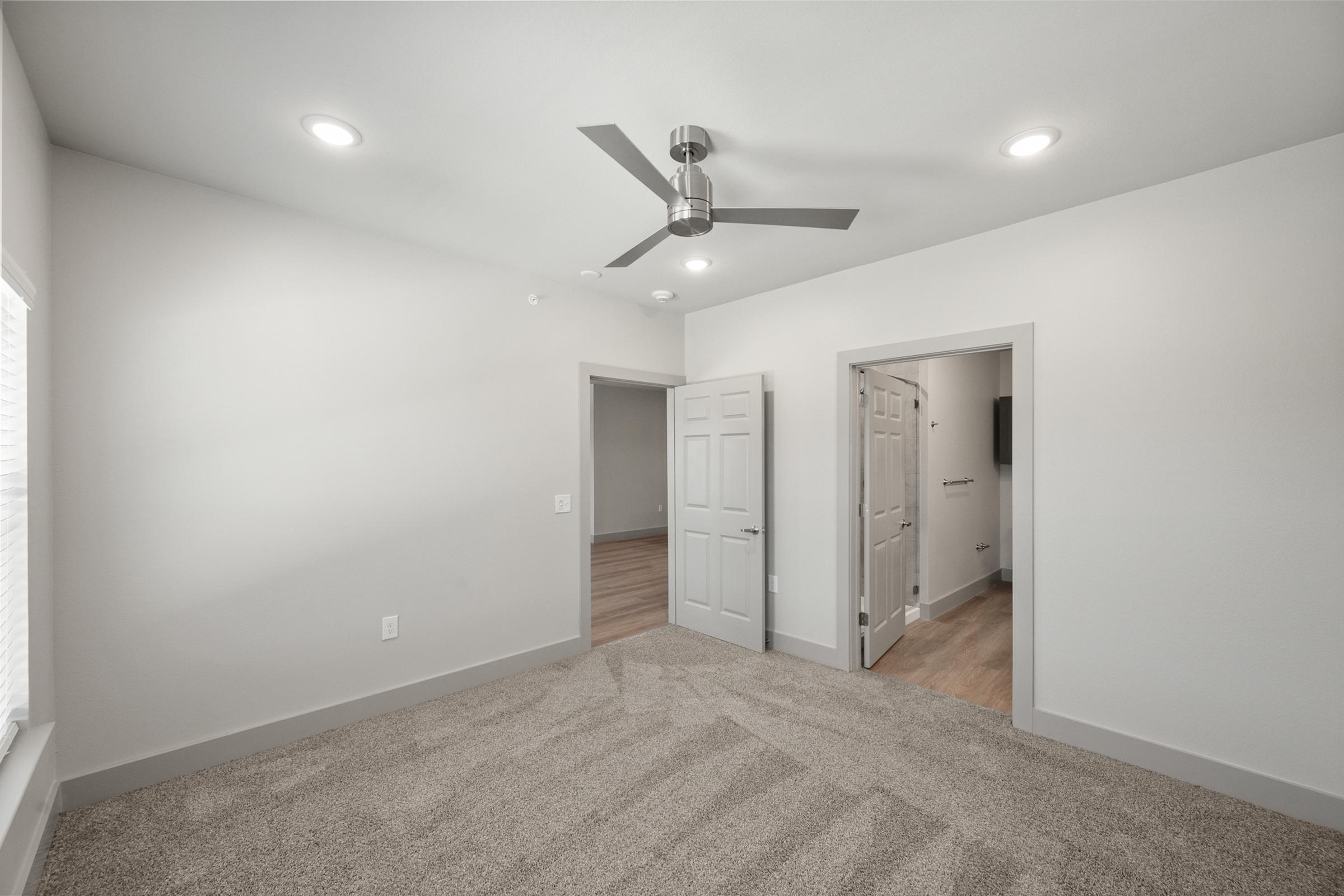 Primary bedroom in the C1 unit with plush carpet, oversized windows, and direct access to an ensuite bathroom and walk-in closet.