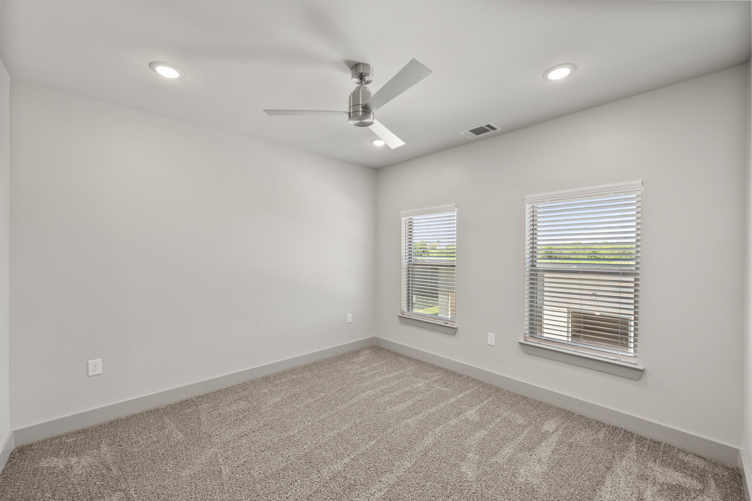 Primary bedroom in the C1 unit with plush carpet, oversized windows, and direct access to an ensuite bathroom and walk-in closet.