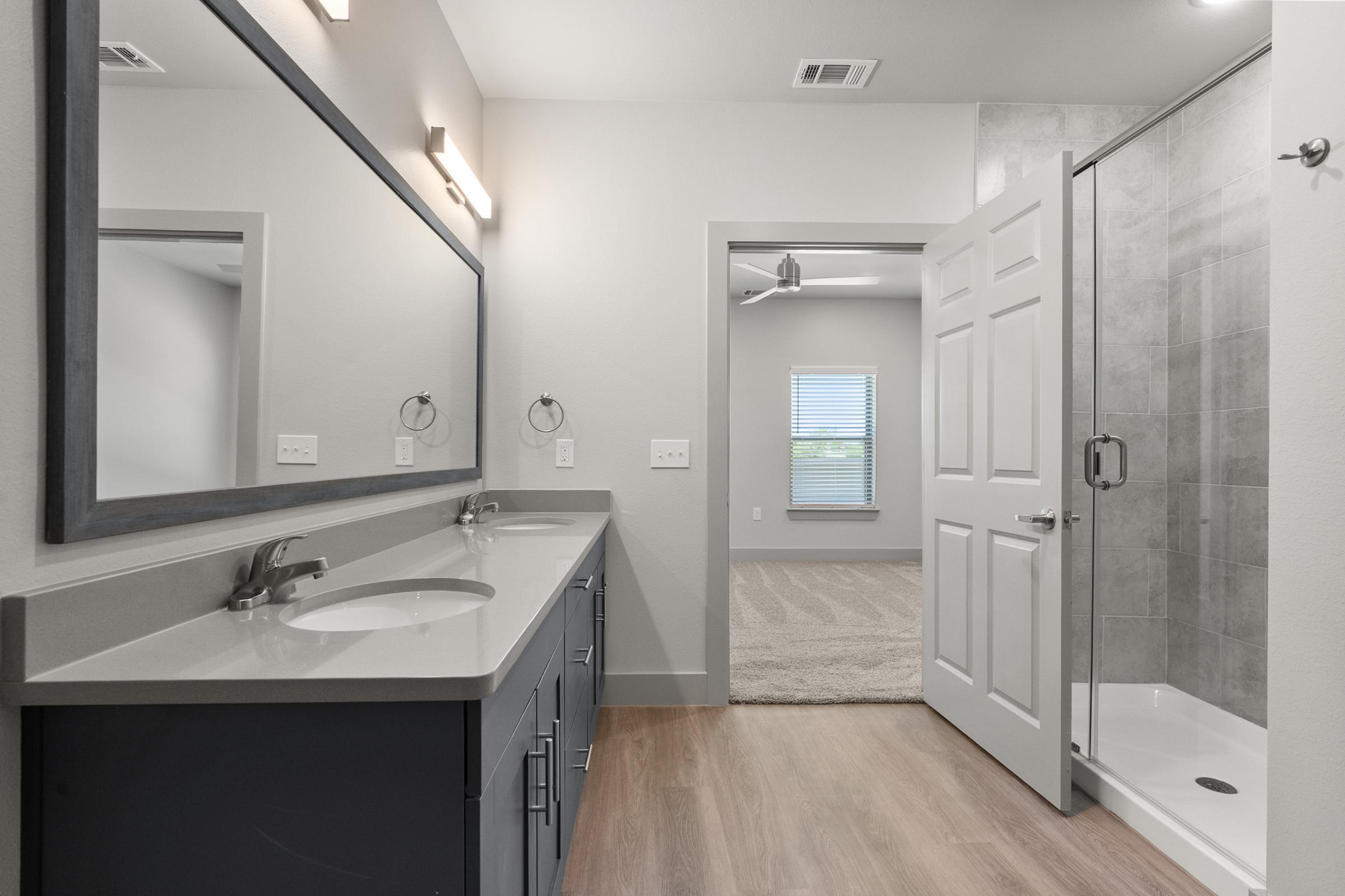 Modern primary bathroom with dual vanities, a walk-in shower, and stylish fixtures, offering a spa-like retreat.