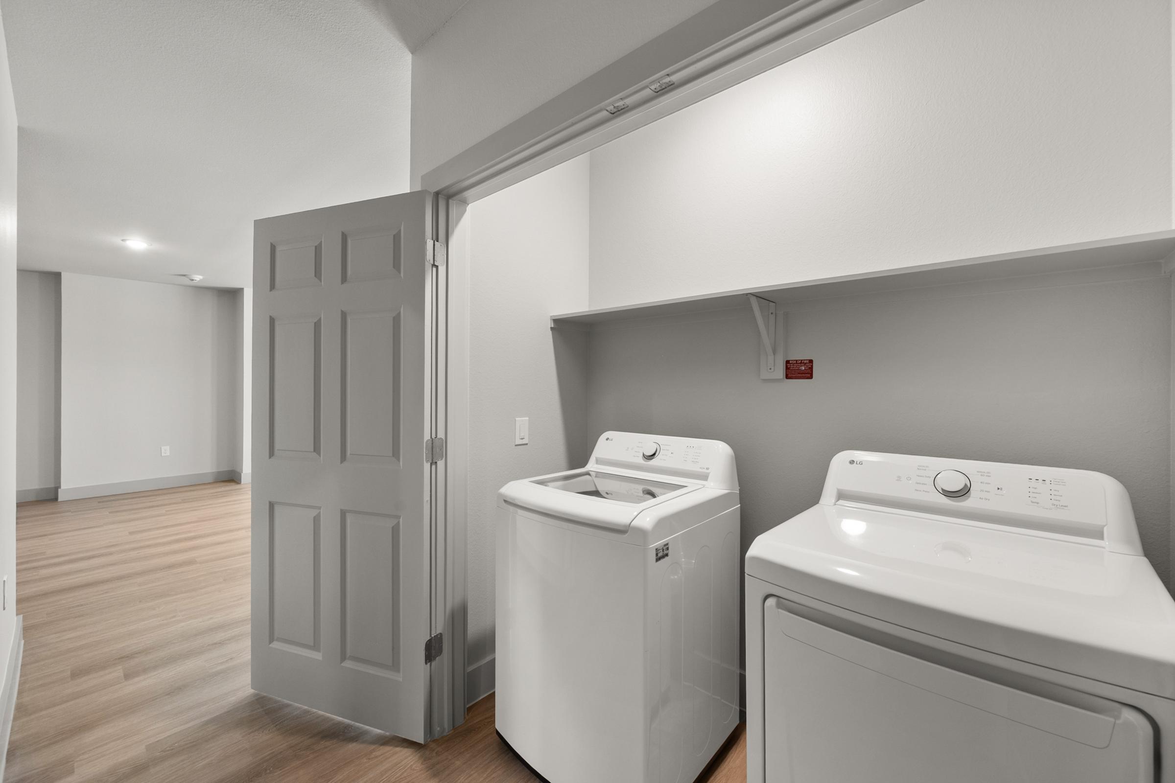 In-unit laundry room in the C1 Floor Plan with full-size washer and dryer and built-in shelving for convenience.