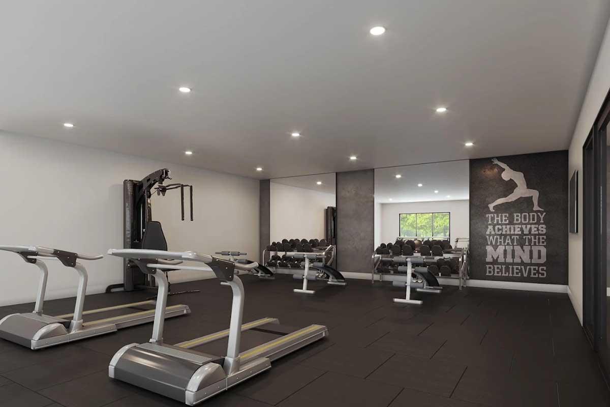 A modern gym interior featuring treadmills, weight training equipment, and a motivational wall mural that reads, "The body achieves what the mind believes." The space is well-lit with a sleek design, including mirrors and a view of additional workout equipment in the background.