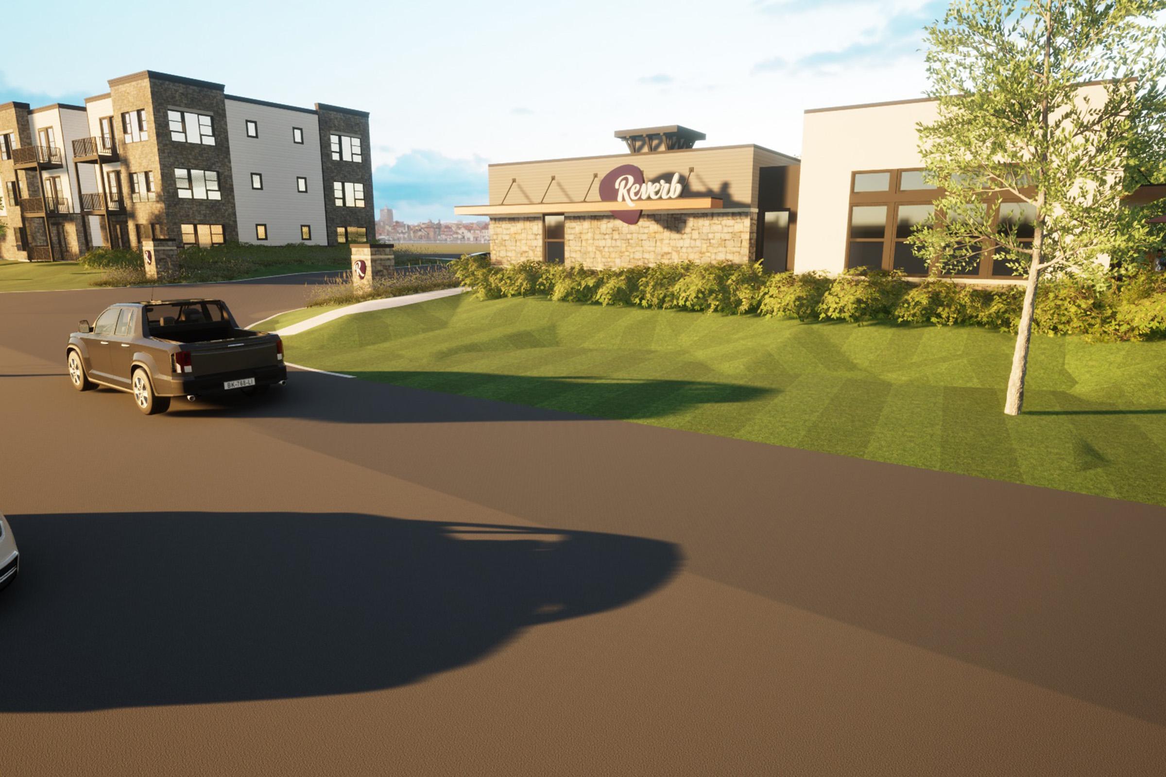 A modern commercial building with the sign "Reverb" is situated in a landscaped area. In the foreground, a black truck is driving on a paved road, while another vehicle is parked nearby. The background features contemporary multi-story residential buildings and a well-maintained lawn under a clear sky.