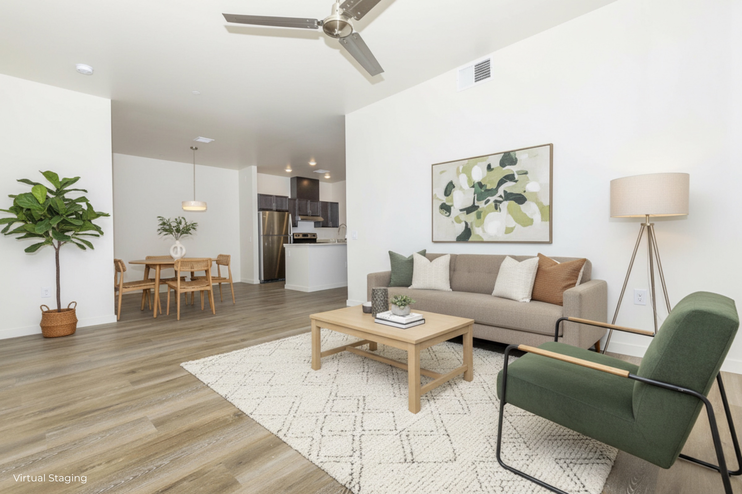 A modern living room with a light-colored sofa, a wooden coffee table, and a green accent chair. A potted plant adds greenery, while a dining area with a table and chairs is visible in the background. The space features neutral walls and a stylish rug, creating a cozy and inviting atmosphere.
