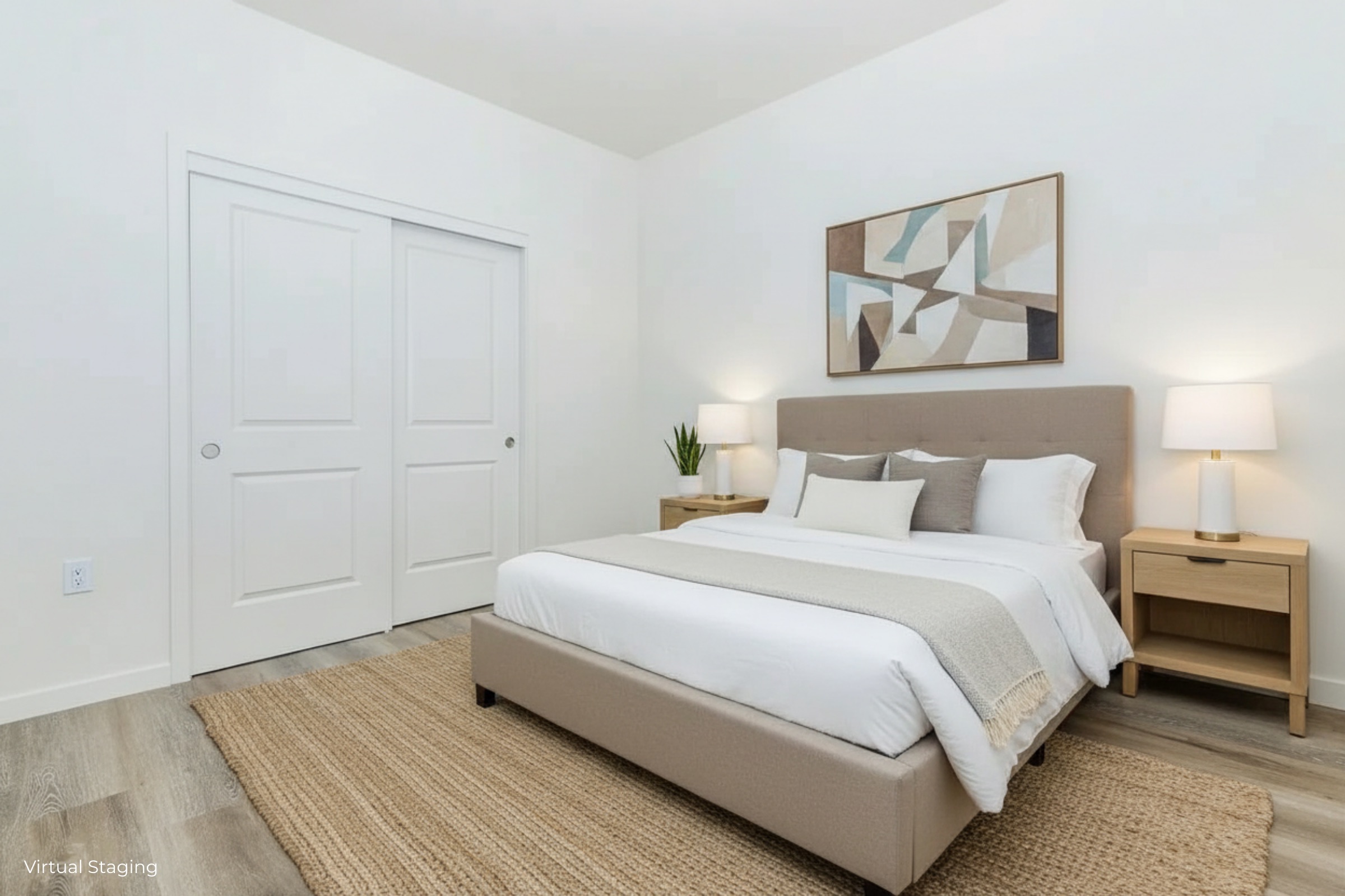 A beautifully staged bedroom featuring a queen-sized bed with a light-colored upholstered headboard. There are two bedside tables with lamps, a neutral-toned rug on the floor, and abstract wall art above the bed. A small plant is positioned near the closet, adding a touch of greenery to the space.