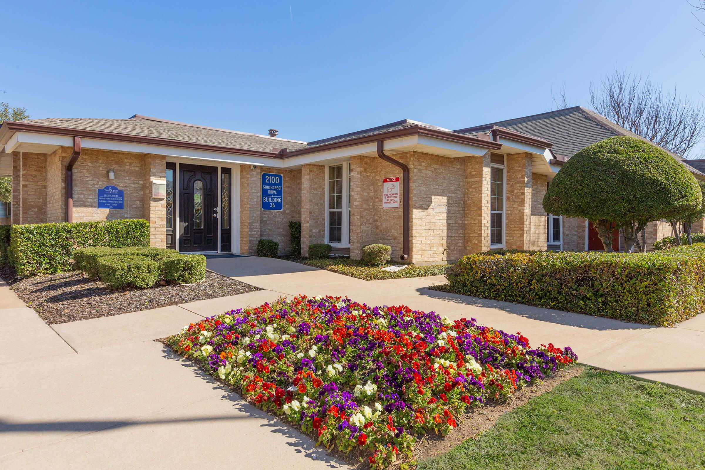 a close up of a flower garden in front of a house