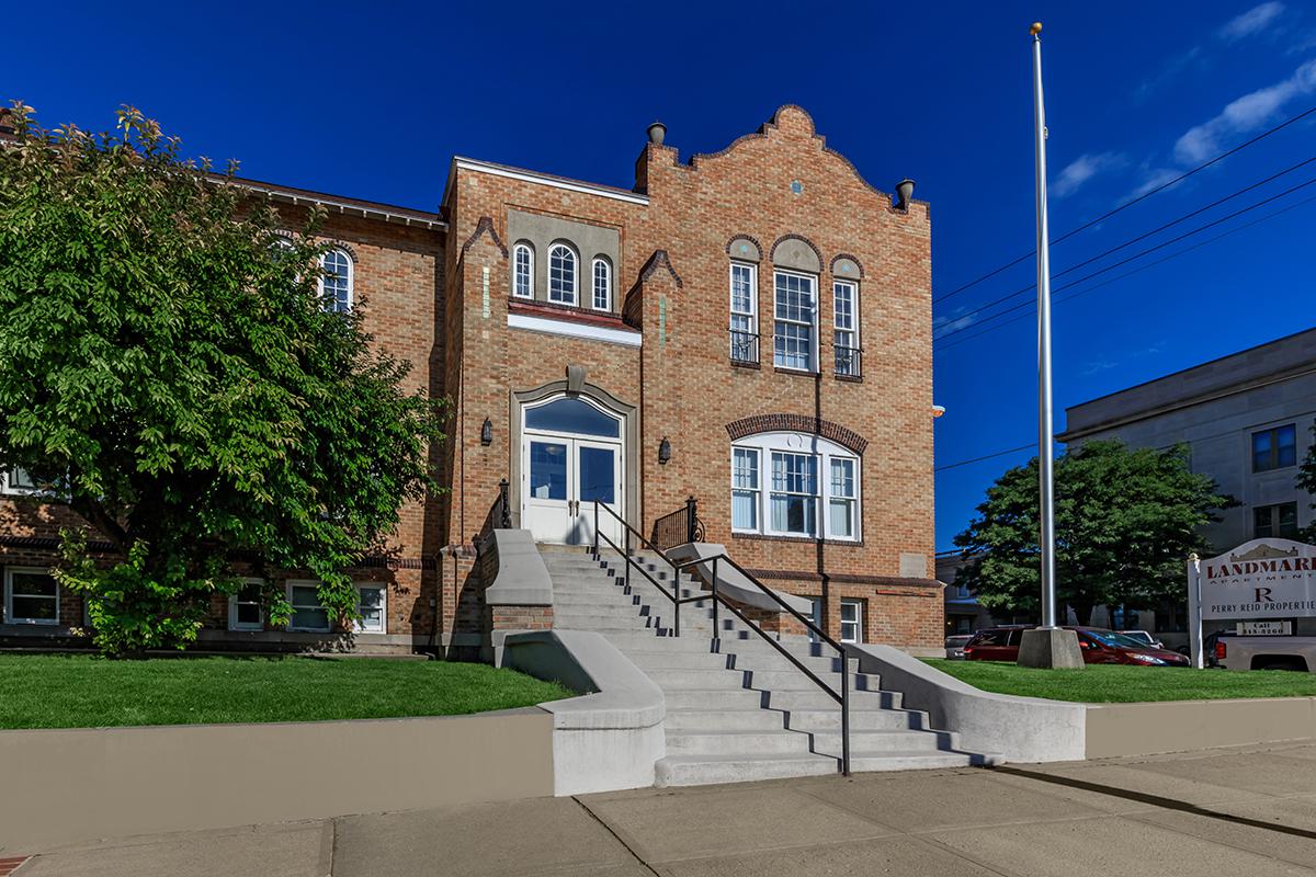 a large brick building with a clock on the side of a road