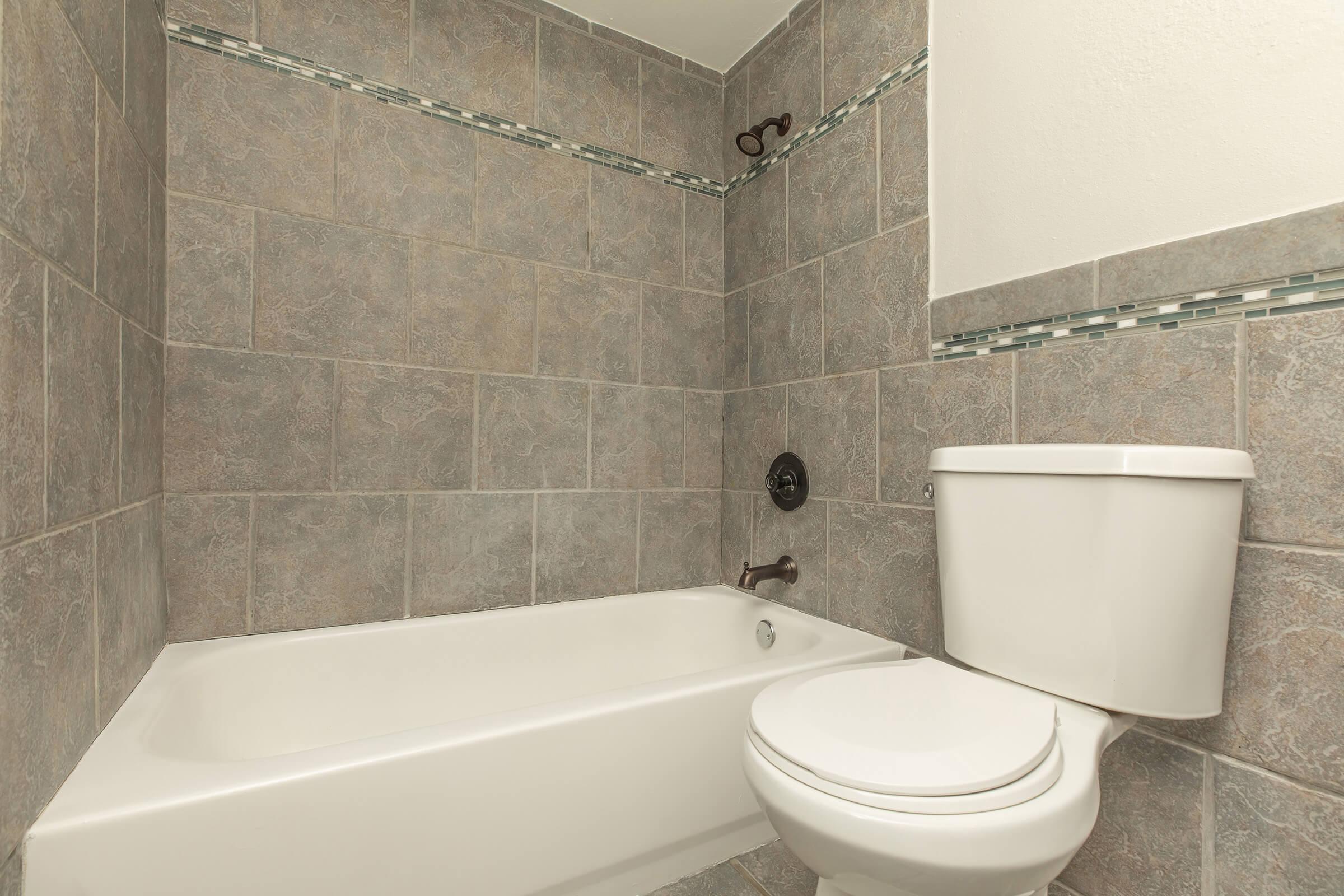 a brown tiled floor next to a shower