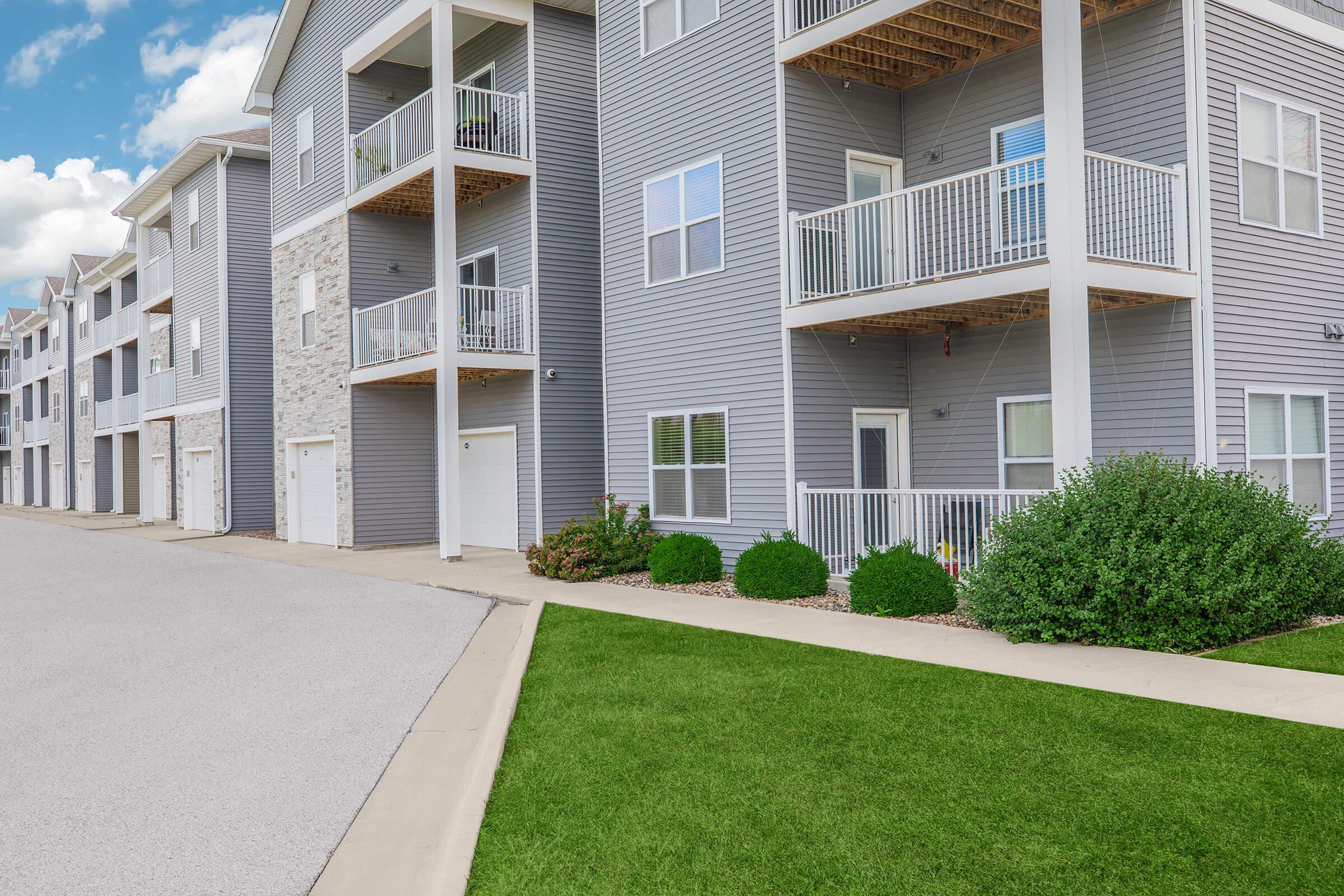 Ground-level view of balconies and garages at The Groves on Devils Glen apartments in Bettendorf, IA