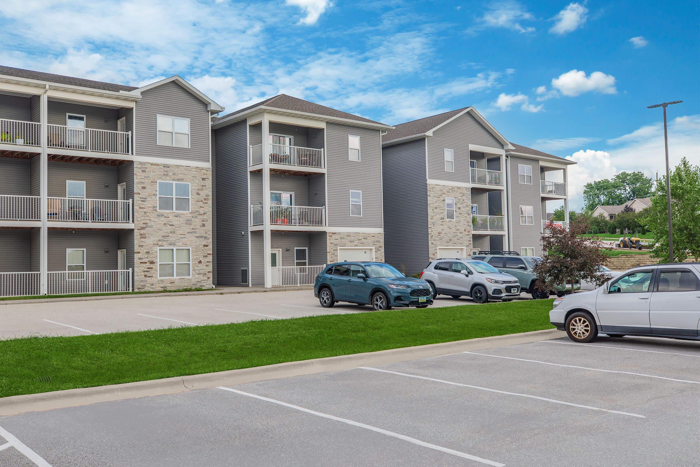 Parking lot view of The Groves on Devils Glen apartments in Bettendorf, IA