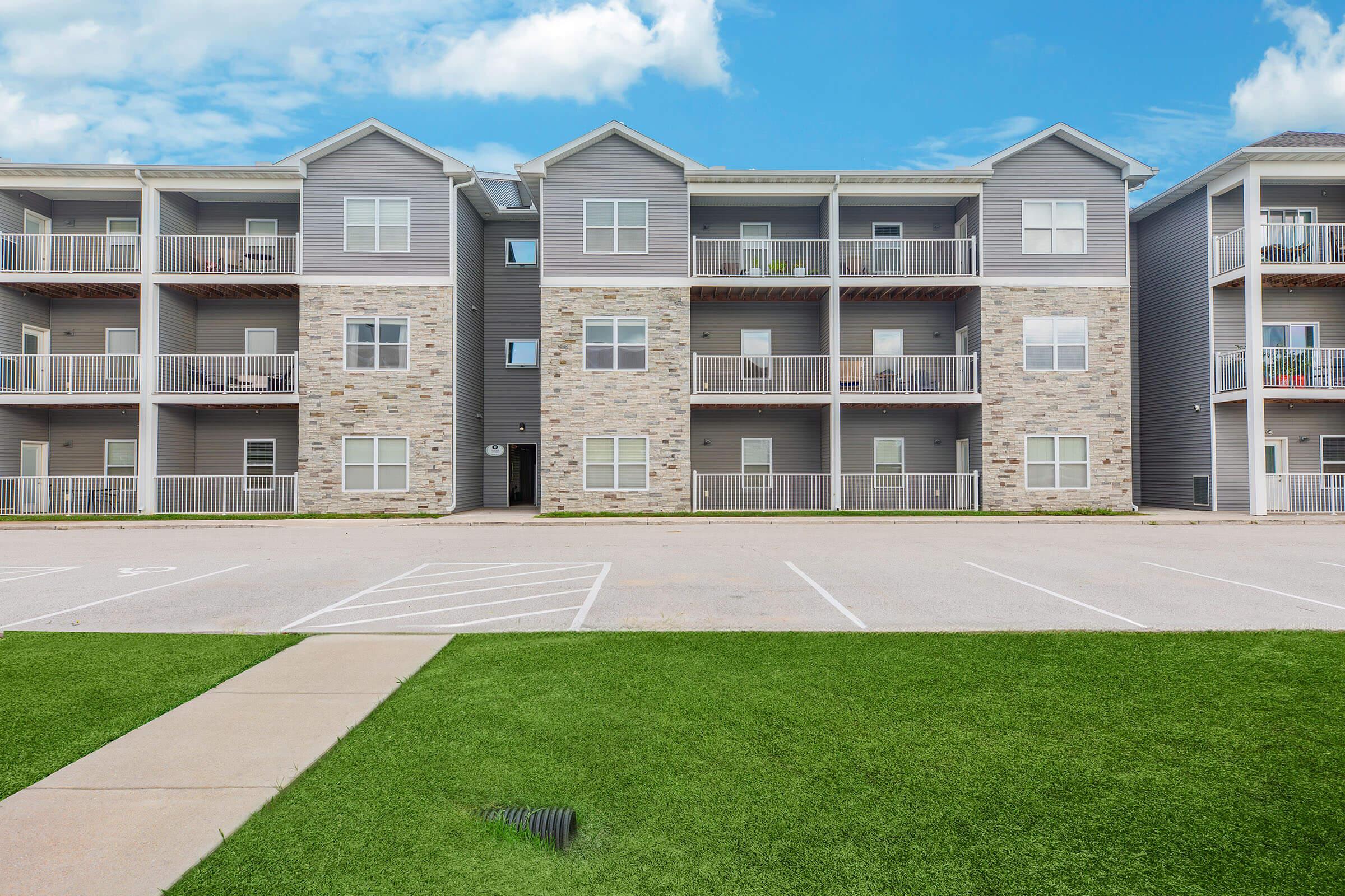 Exterior parking and three-story apartments at The Groves on Devils Glen in Bettendorf, IA