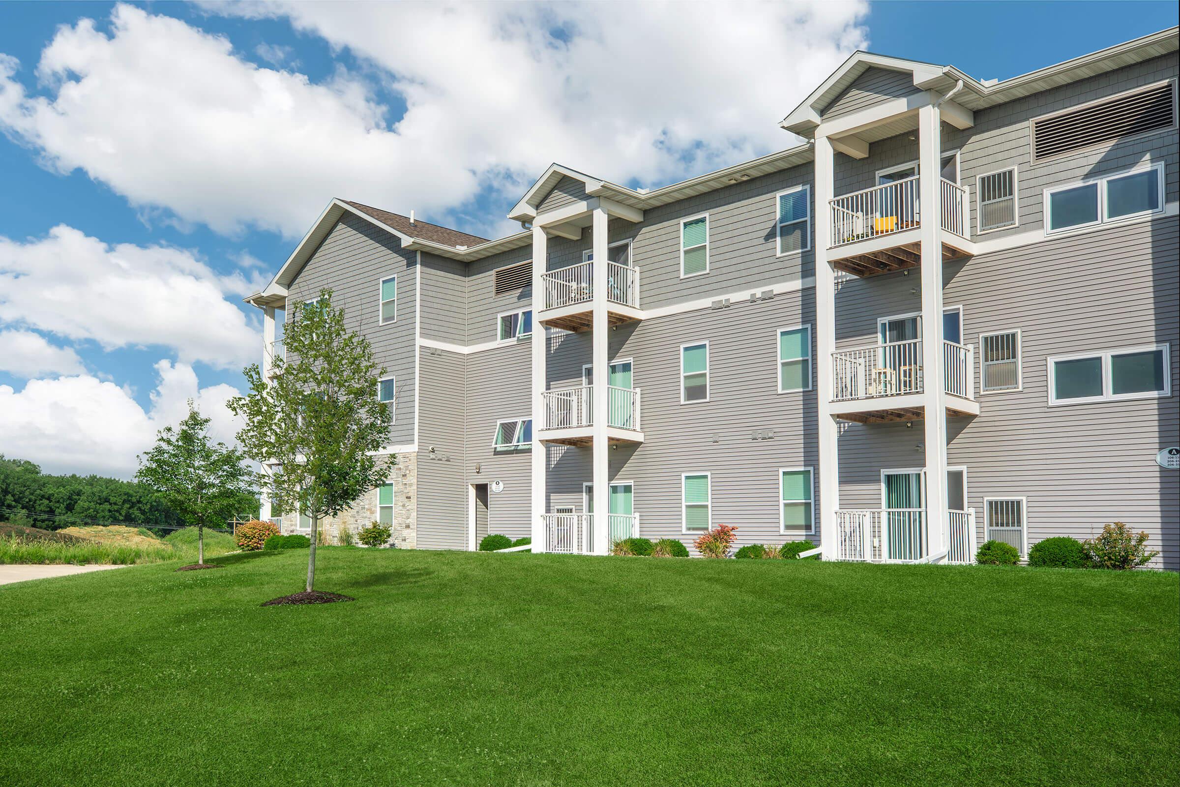 Exterior of new three-story apartments with balconies at The Groves on Devils Glen in Bettendorf, IA