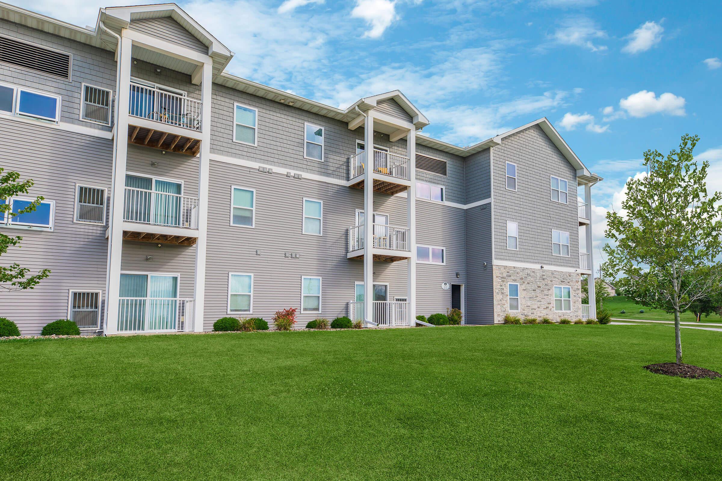 Front view of new apartments with manicured lawn at The Groves on Devils Glen in Bettendorf, IA