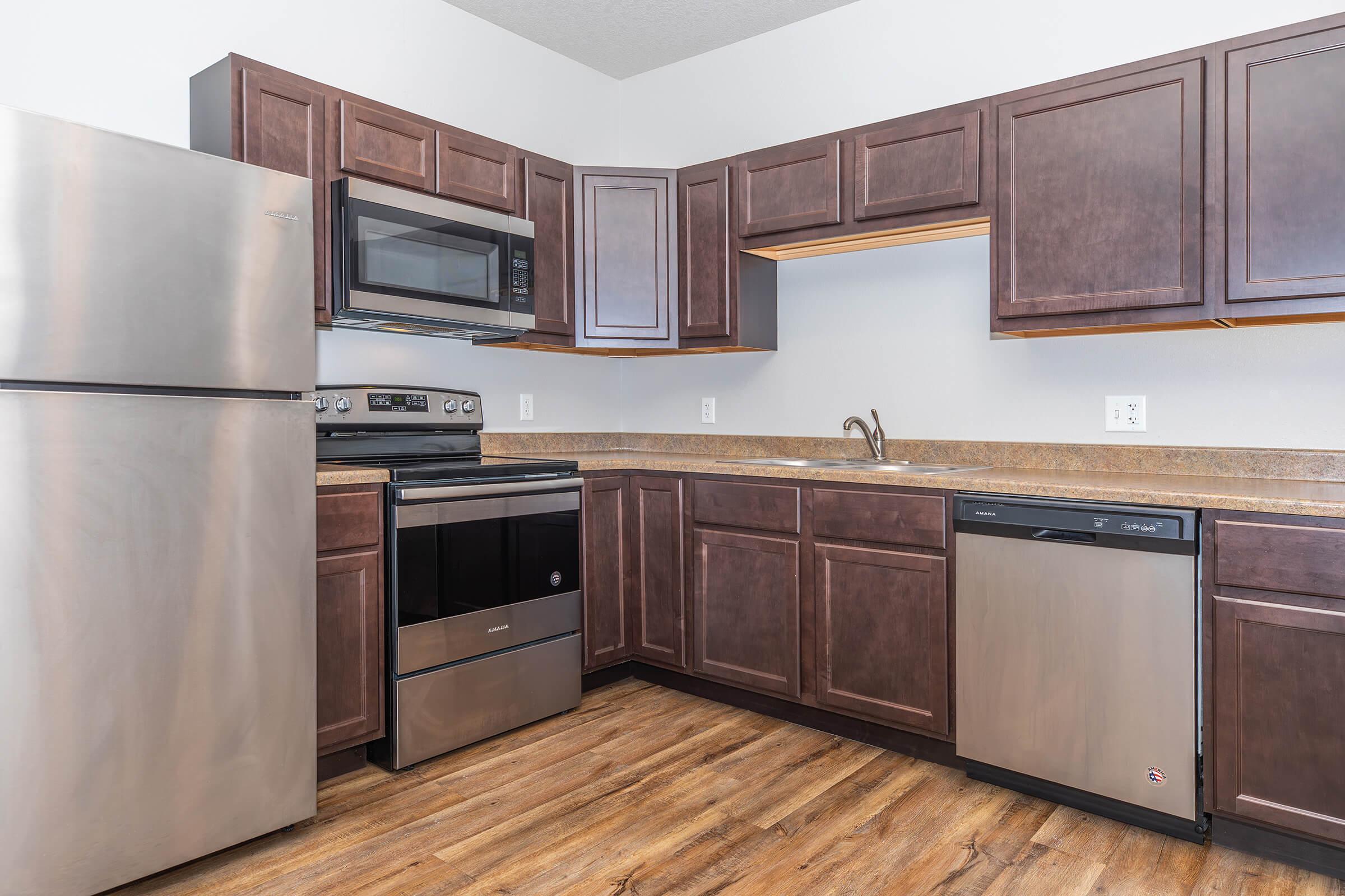 Modern kitchen with stainless steel appliances, dark cabinetry, and ample counter space at The Groves on Devils Glen in Bettendorf, IA