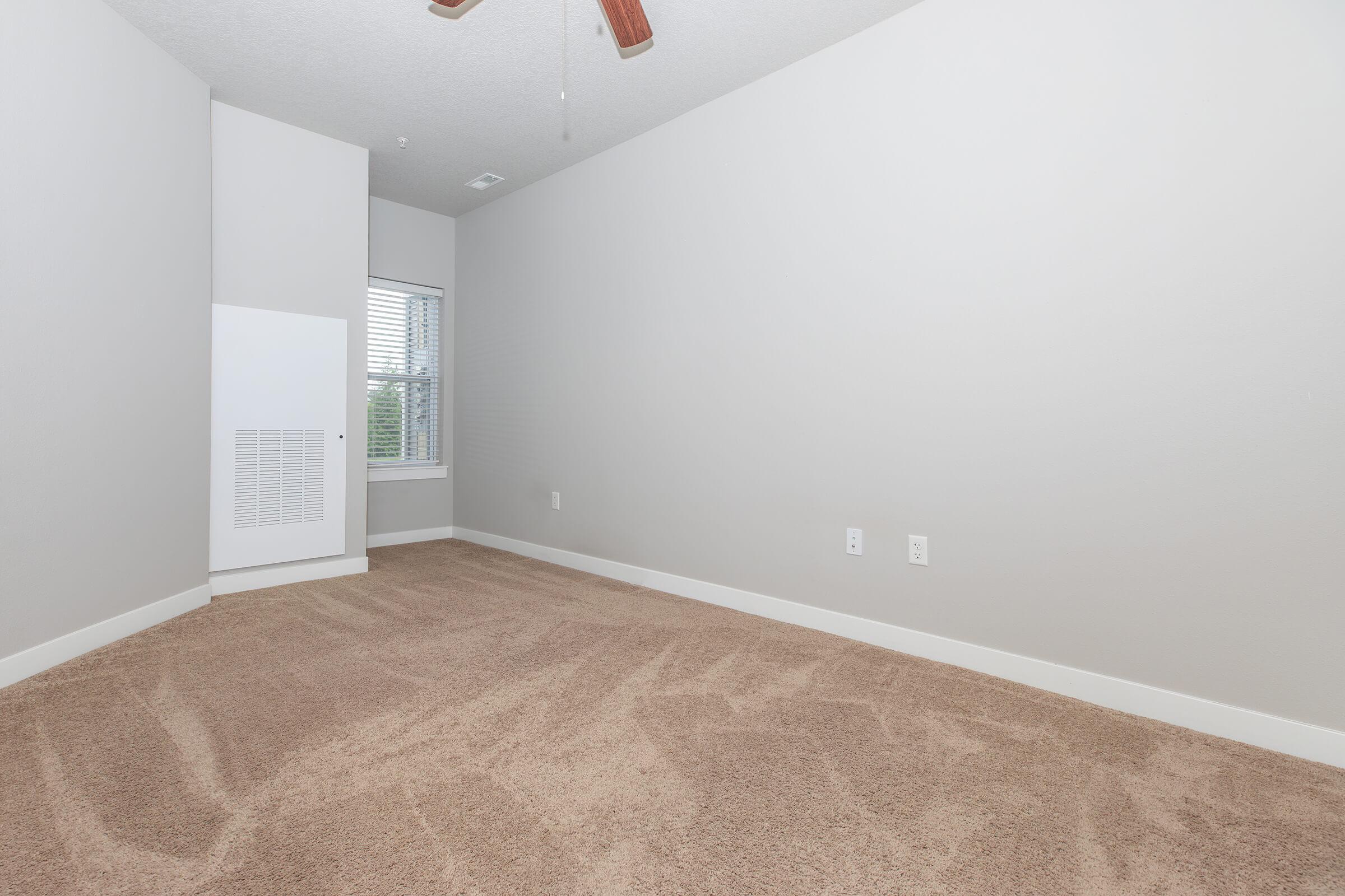 Carpeted bedroom with neutral walls and ceiling fan at The Groves on Devils Glen in Bettendorf, IA